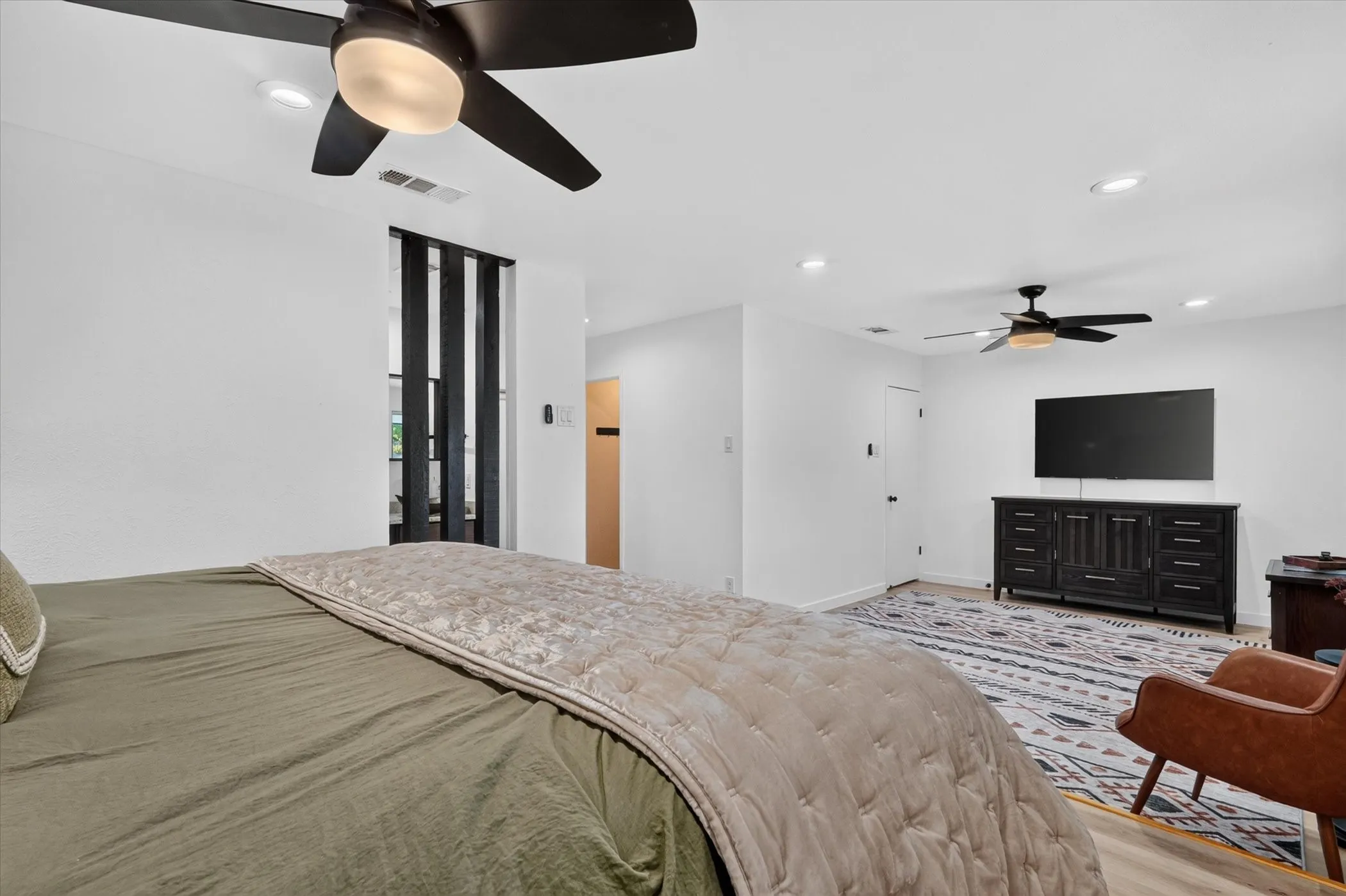 Recessed lighting, ceiling fans, and light wood-finish flooring create a bright and airy atmosphere