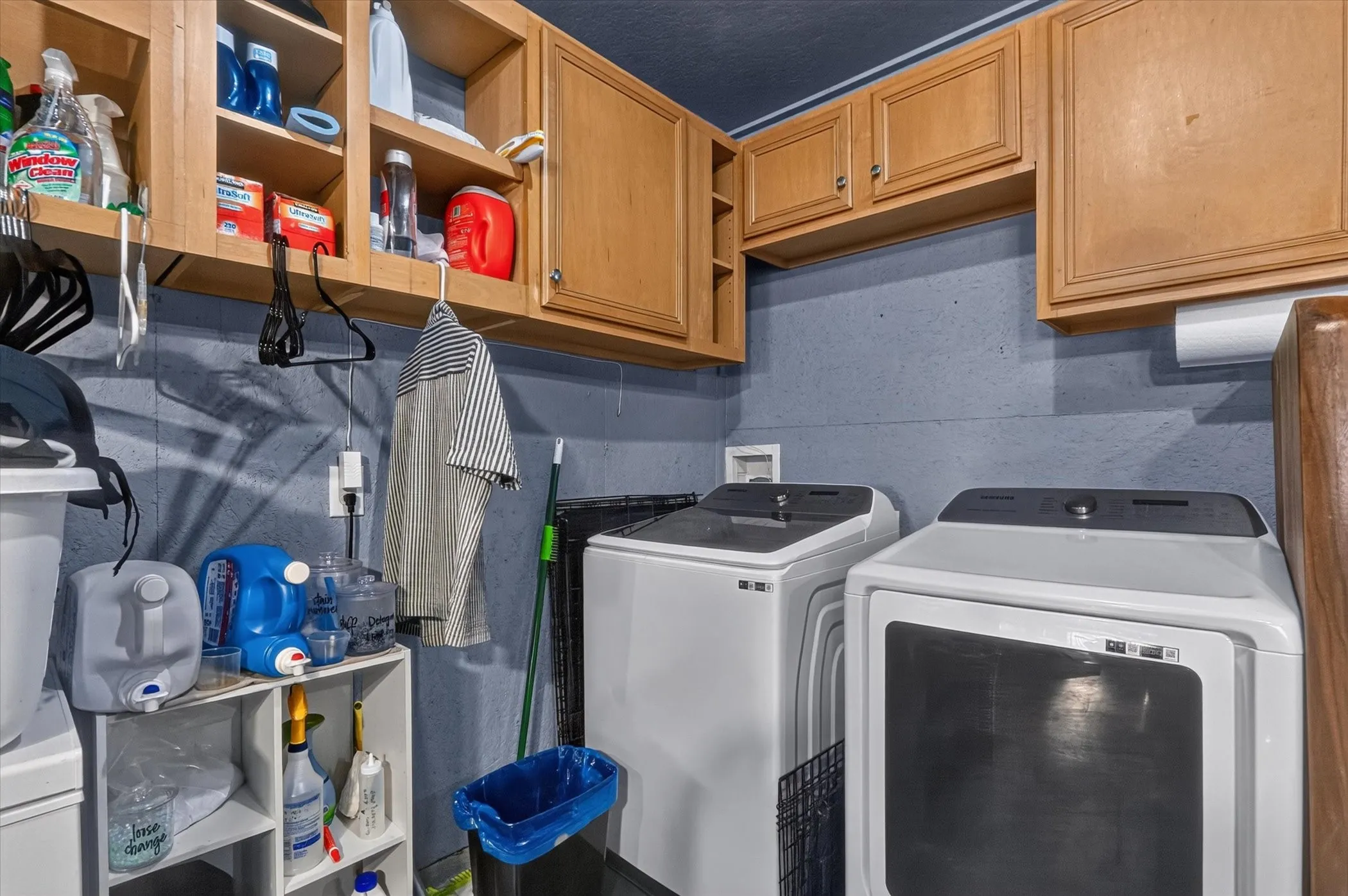 Laundry area featuring wall-mounted cabinetry, a pair of appliances, and an overhead lighting fixture