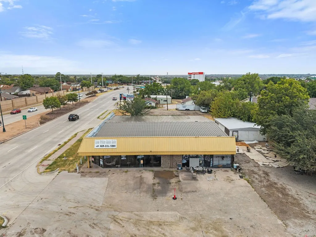 Commercial building featuring an expansive concrete lot, a yellow metal awning, and a metal roof