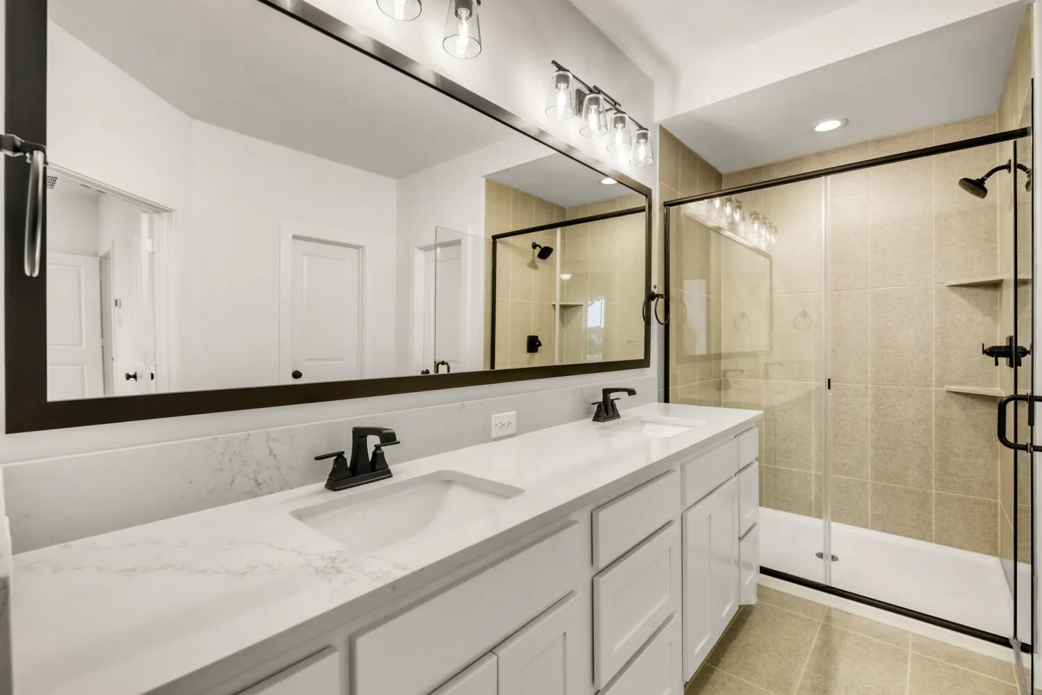 Dual vanity with white cabinetry and integrated sinks, quartz countertops, a large framed mirror, and matte black fixtures
