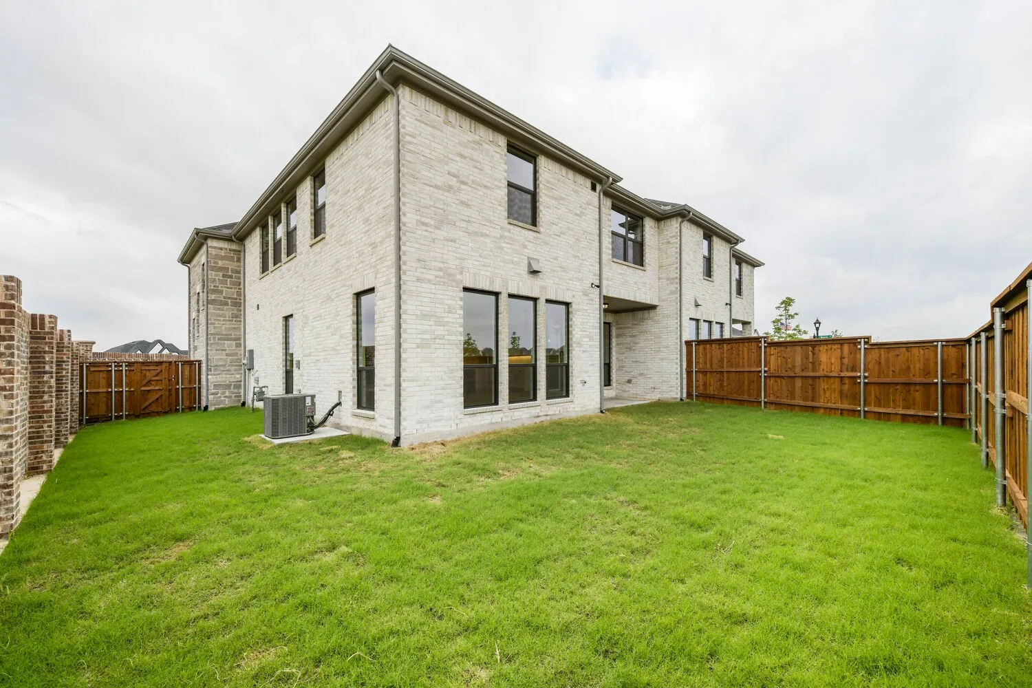 Expansive green lawn with a white brick exterior and dark-framed windows