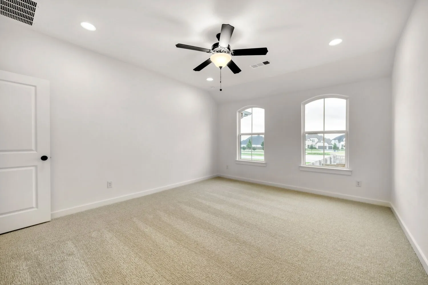 Wall-to-wall carpeting, dual arched windows, recessed lighting, and a ceiling fan with integrated light fixture