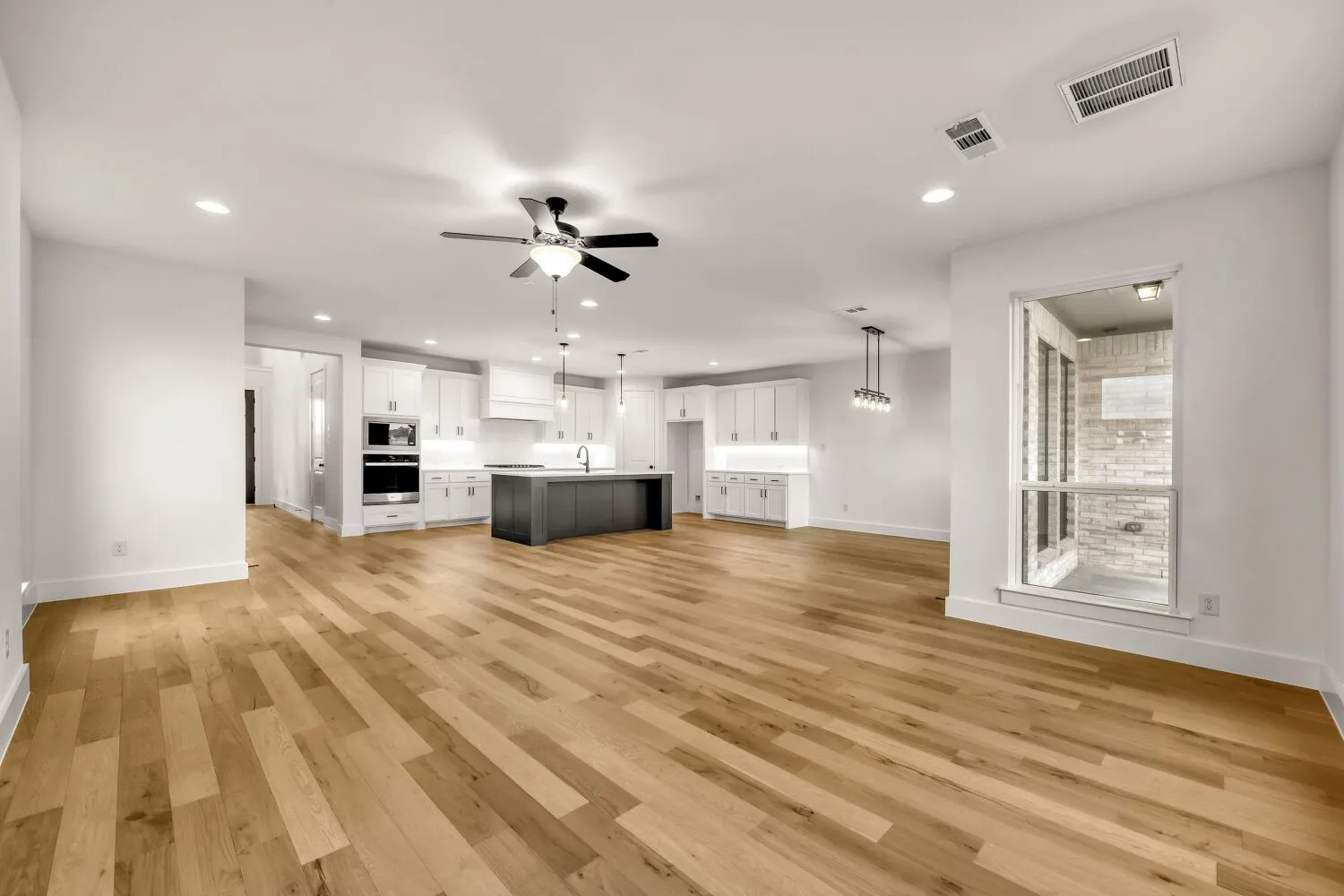 Open-concept living area with wood-finish flooring, recessed lighting, and a modern ceiling fan