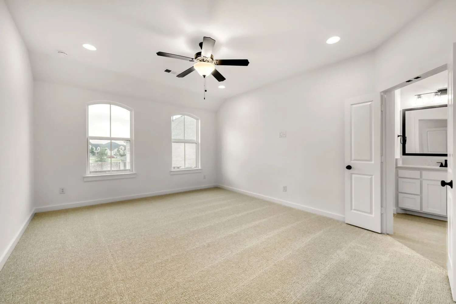 Main bedroom with carpeting, dual arched windows, recessed lighting, and a ceiling fan with integrated light fixture