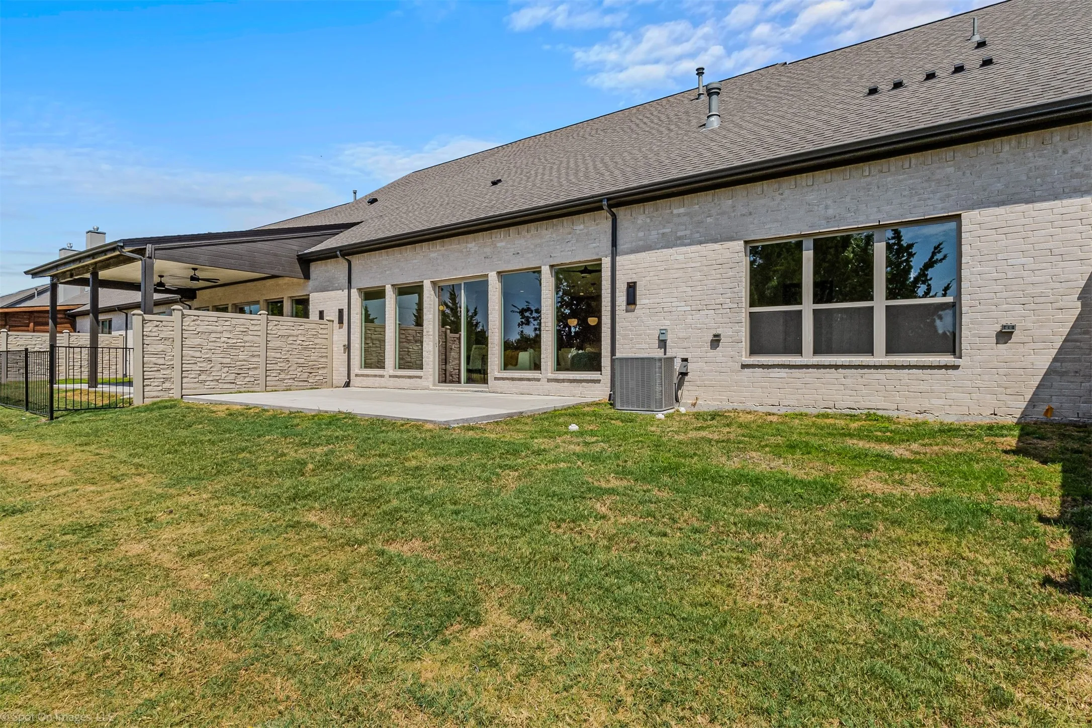 Brick exterior with multiple windows and a large patio