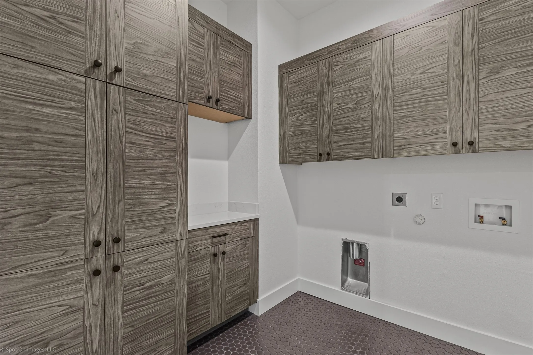 Built-in wood-finish cabinetry, white countertop, hexagon tile flooring, and crisp white walls