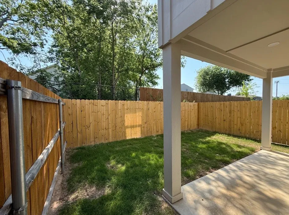 Covered patio with a concrete surface, enclosed by a wood privacy fence