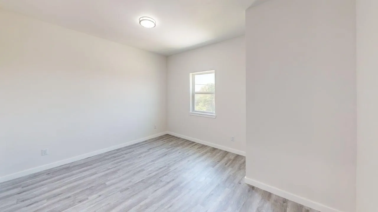 Neutral wall paint, wood-finish flooring, recessed lighting, and a single window