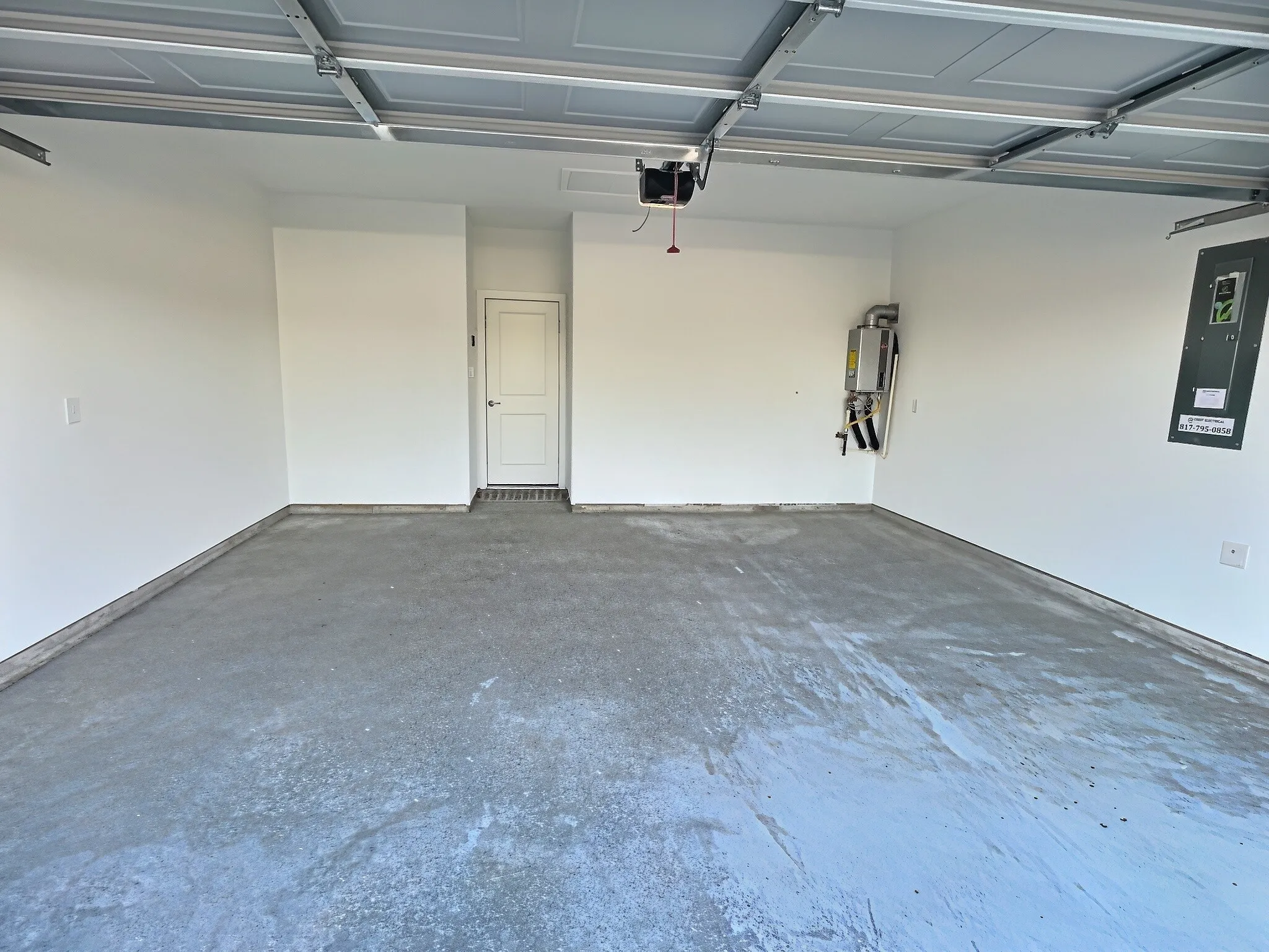 Spacious garage with concrete flooring, automatic garage door opener, and a panel door entry