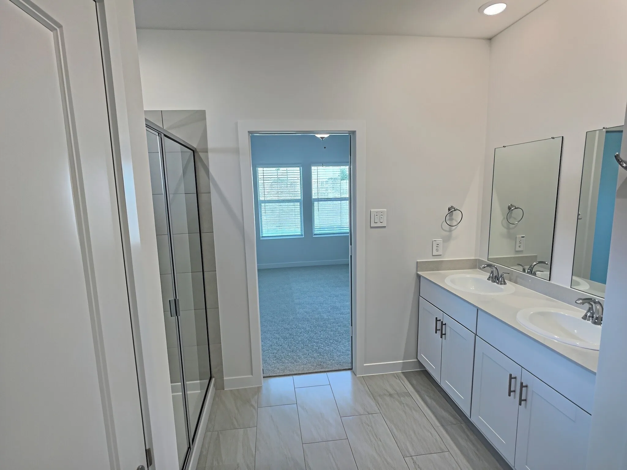 Dual vanity with undermount sinks and chrome fixtures, frameless mirrors, and overhead recessed lighting