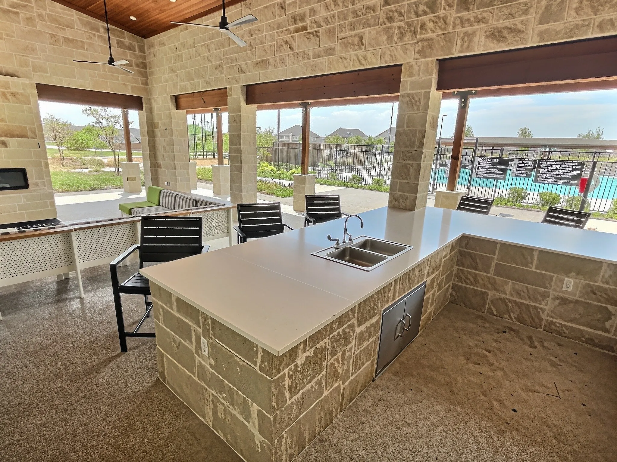Outdoor gathering area featuring stone-clad walls, a wood-finish ceiling, and ceiling fans