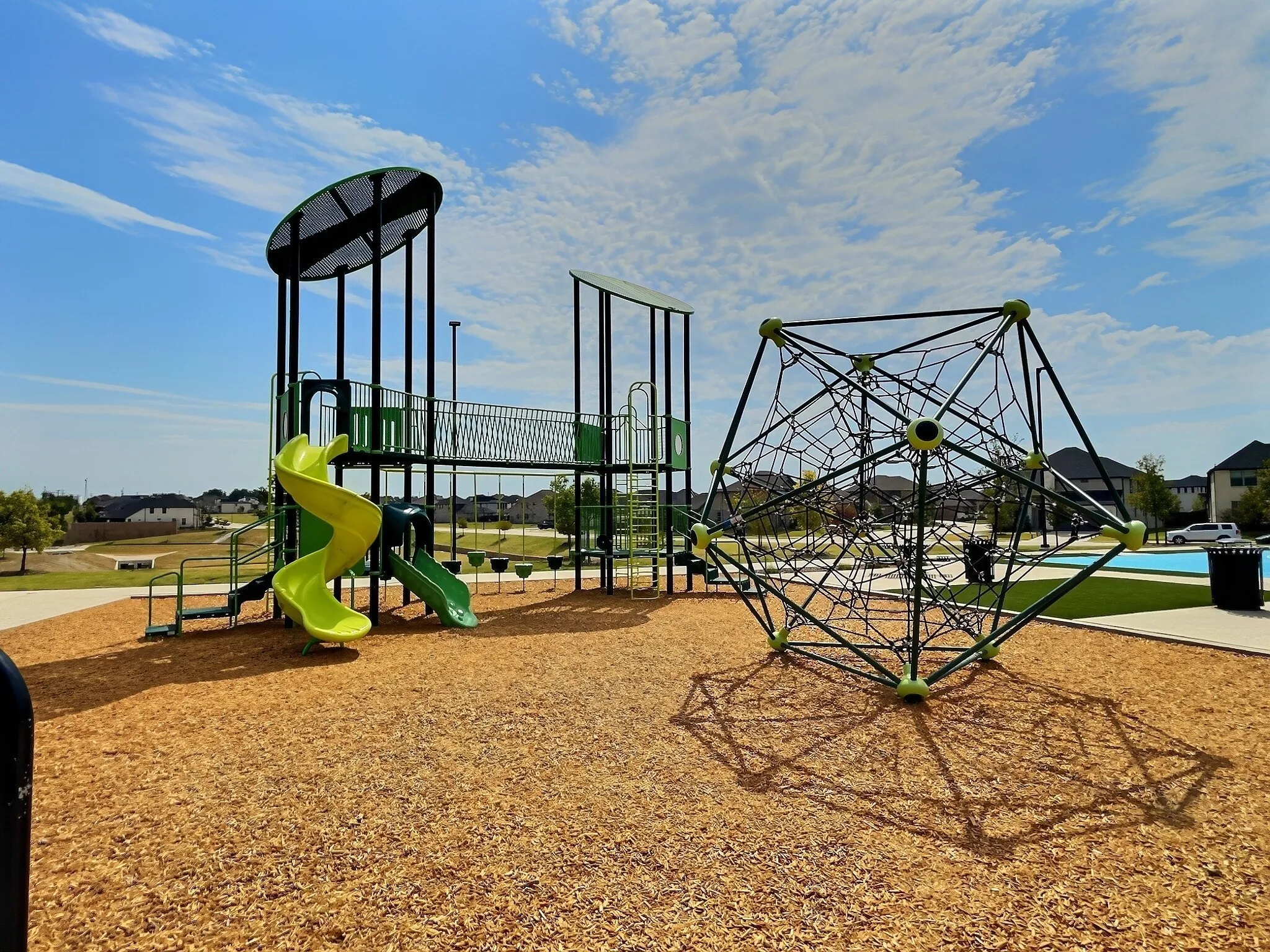 Playground with multiple slides, climbing structure, and wood chip surfacing