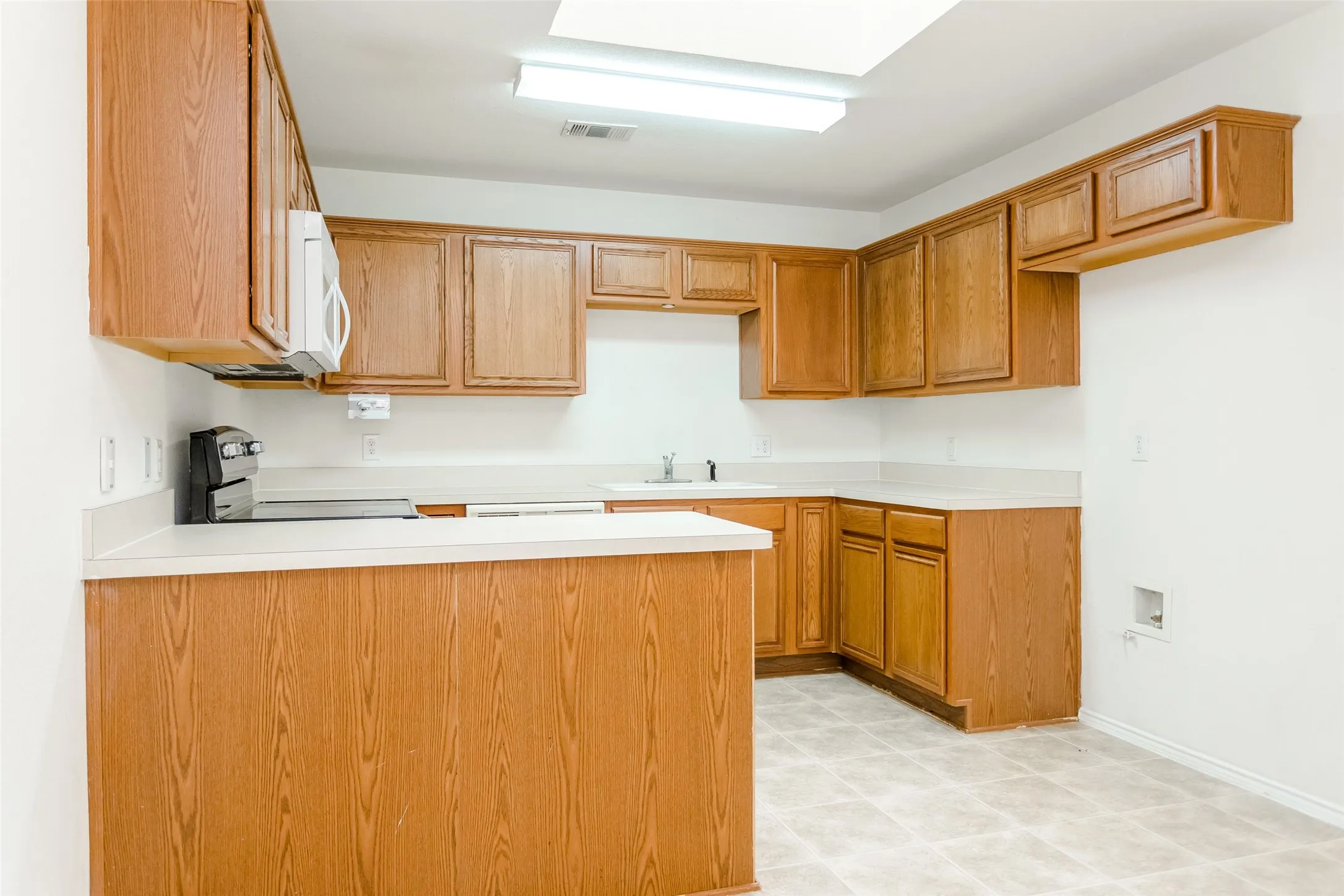 Kitchen featuring light tile patterned flooring, white appliances, sink, and kitchen peninsula
