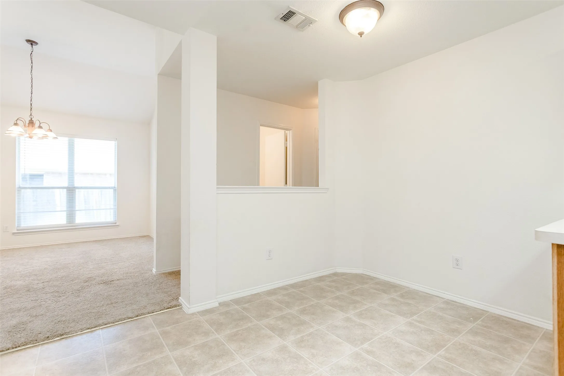 Spare room with light tile patterned floors and an inviting chandelier