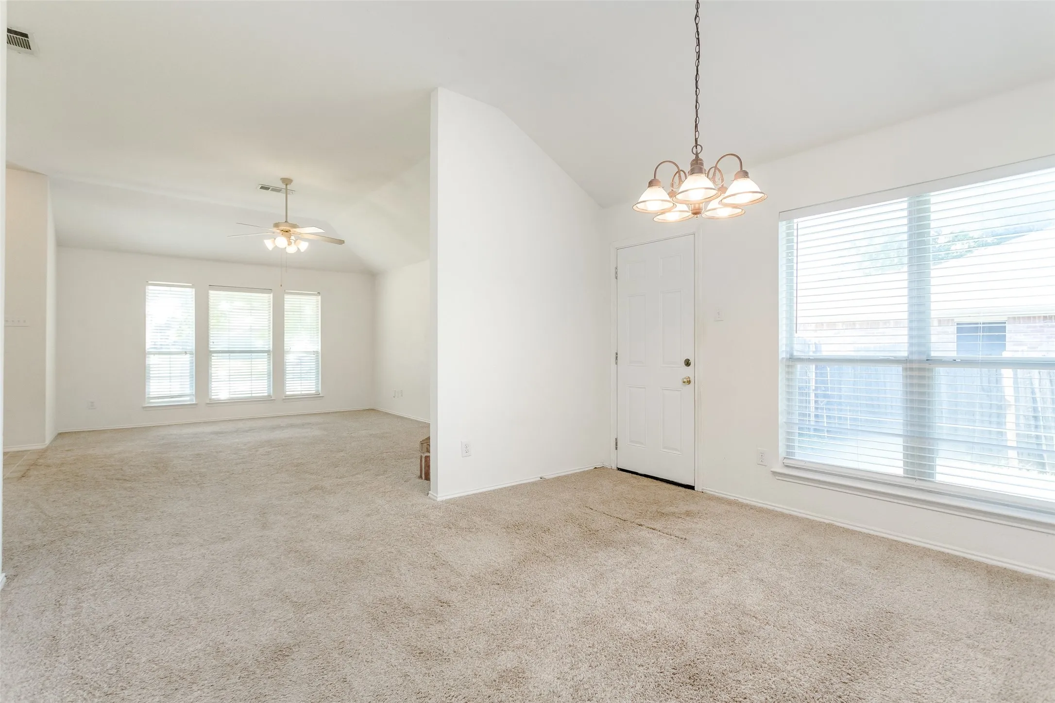 Empty room featuring lofted ceiling, a healthy amount of sunlight, and light colored carpet