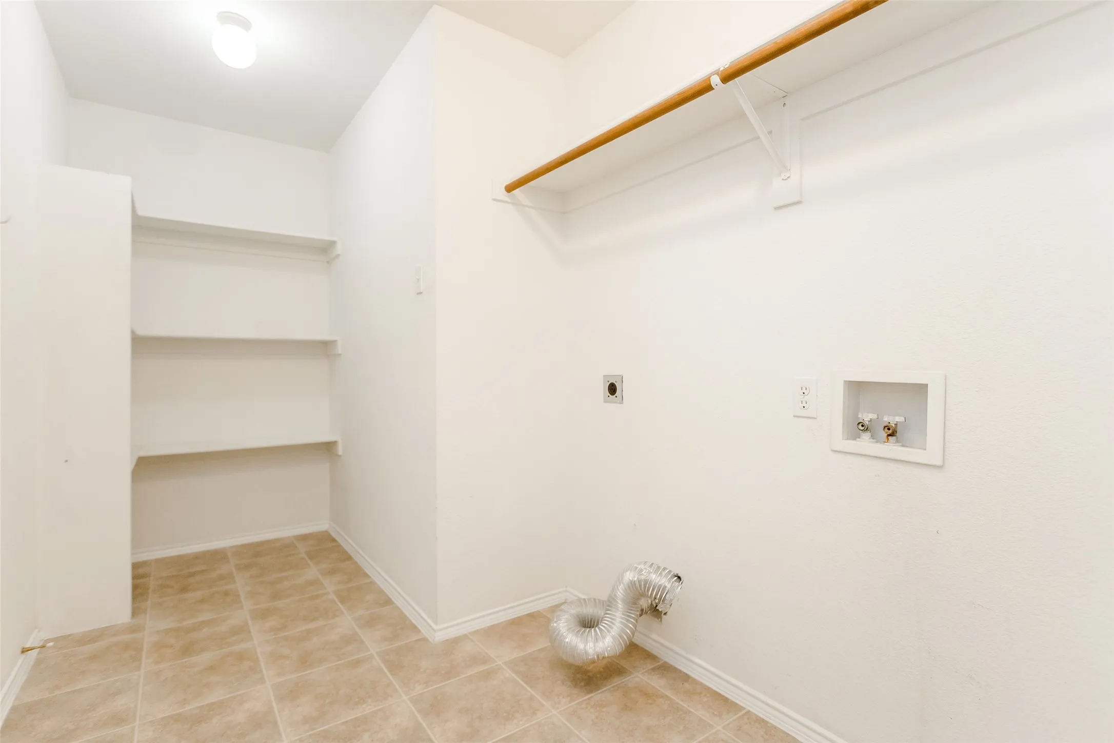 Clothes washing area featuring light tile patterned flooring, hookup for a washing machine, and electric dryer hookup