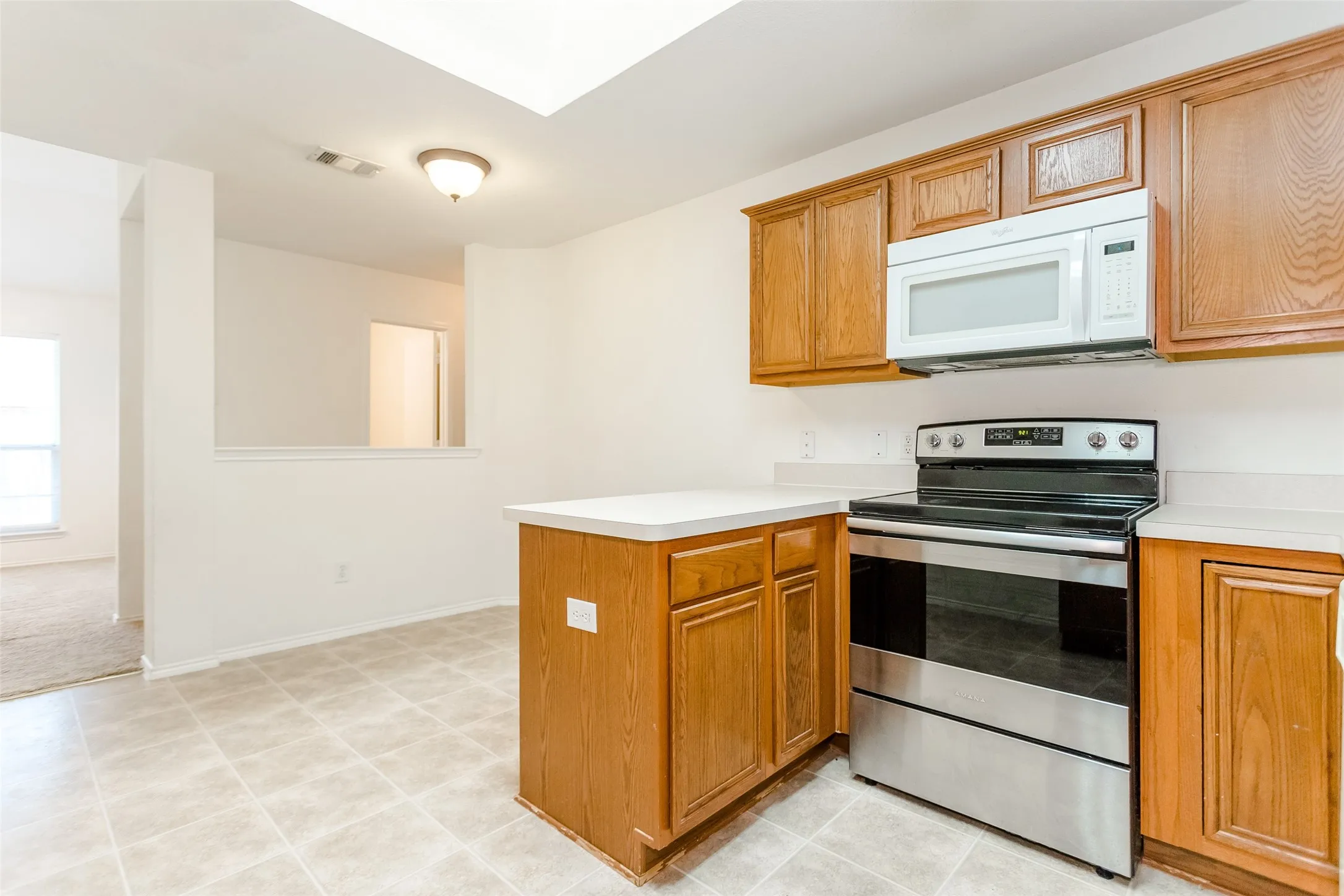 Kitchen featuring stainless steel electric range oven, kitchen peninsula, and light colored carpet