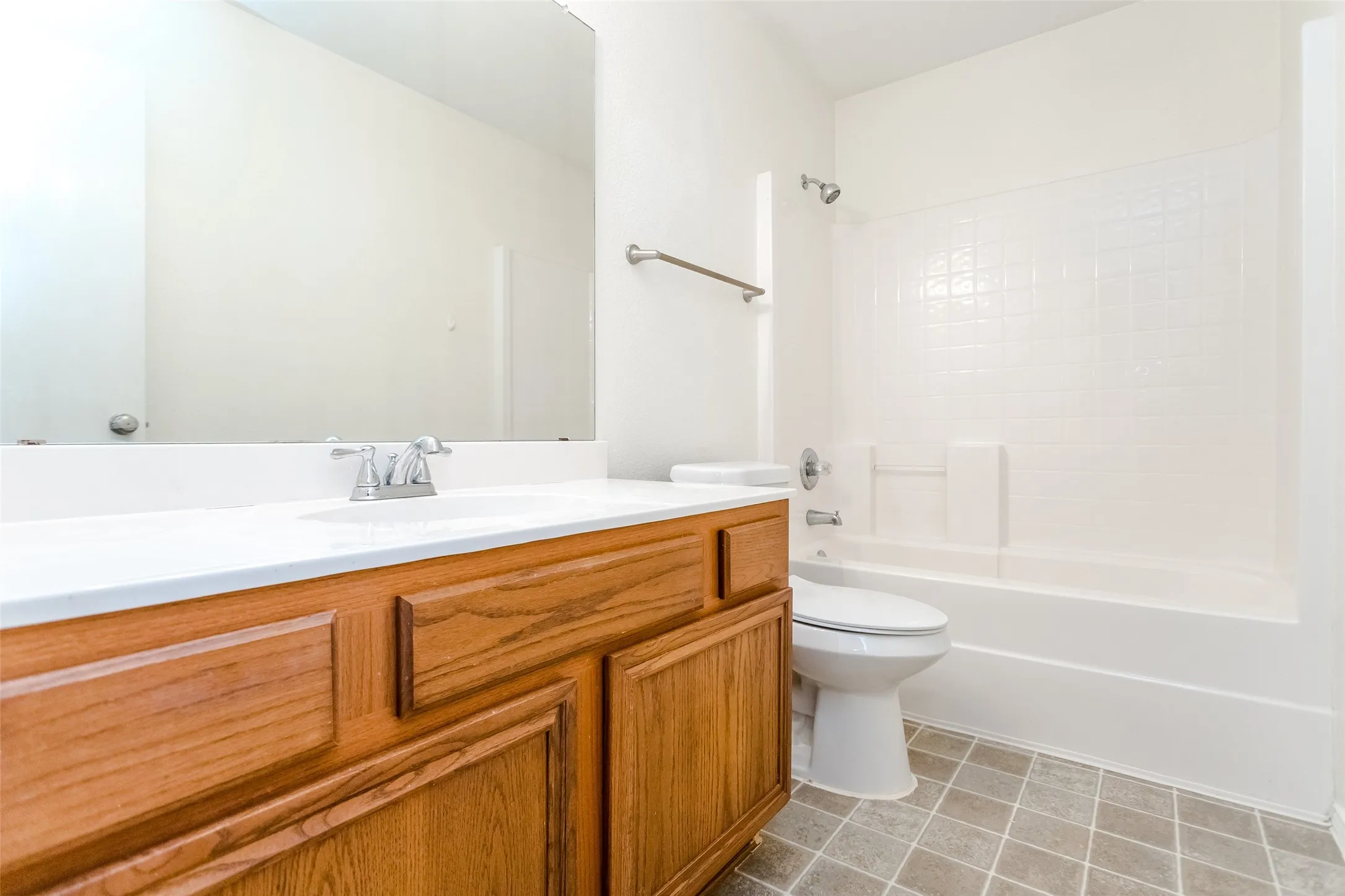 Full bathroom with tile patterned flooring, washtub / shower combination, toilet, and vanity
