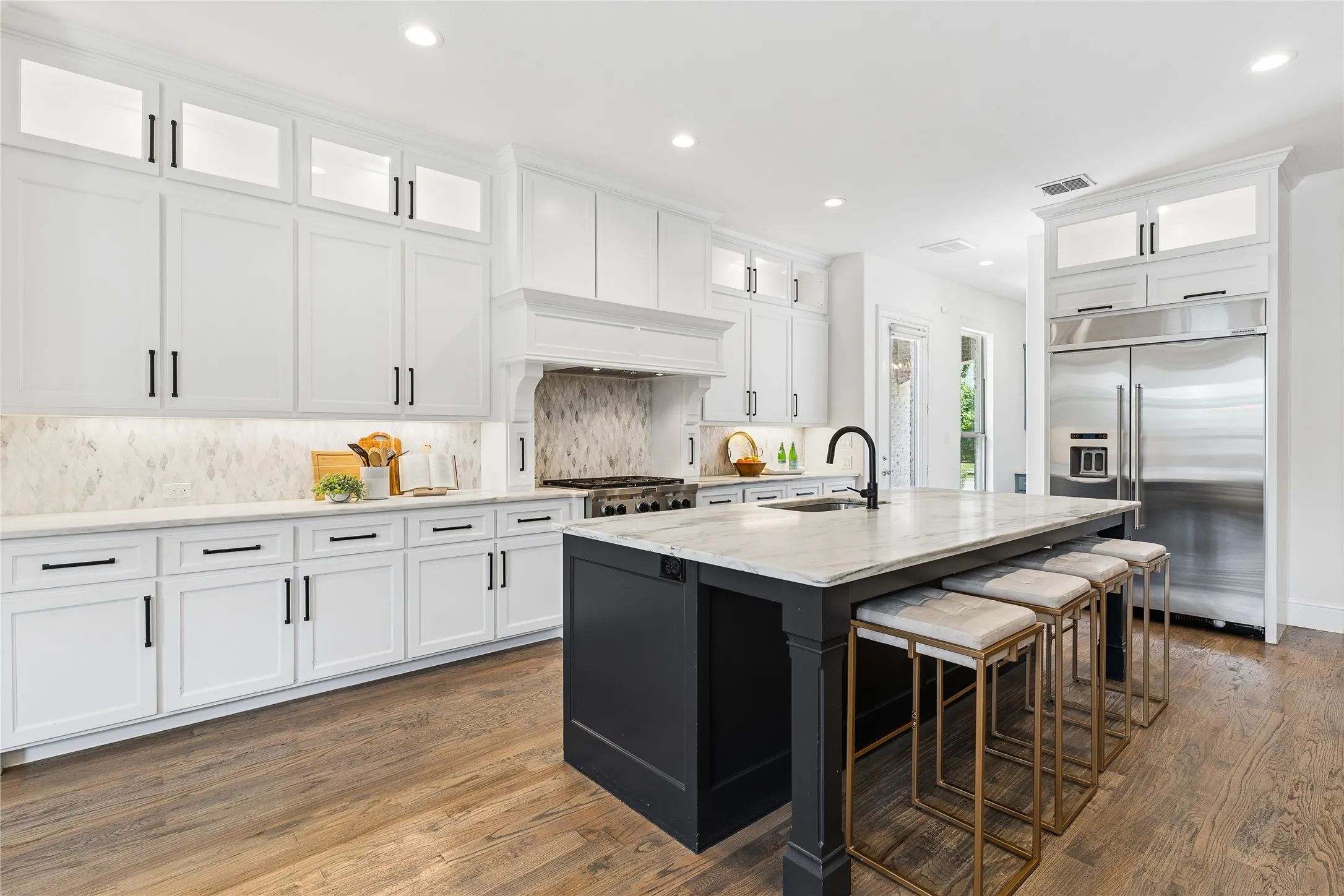 Chef’s kitchen with 6 burner gas cooktop, double oven, oversized island, range hood, and walk-in pantry with planning station.