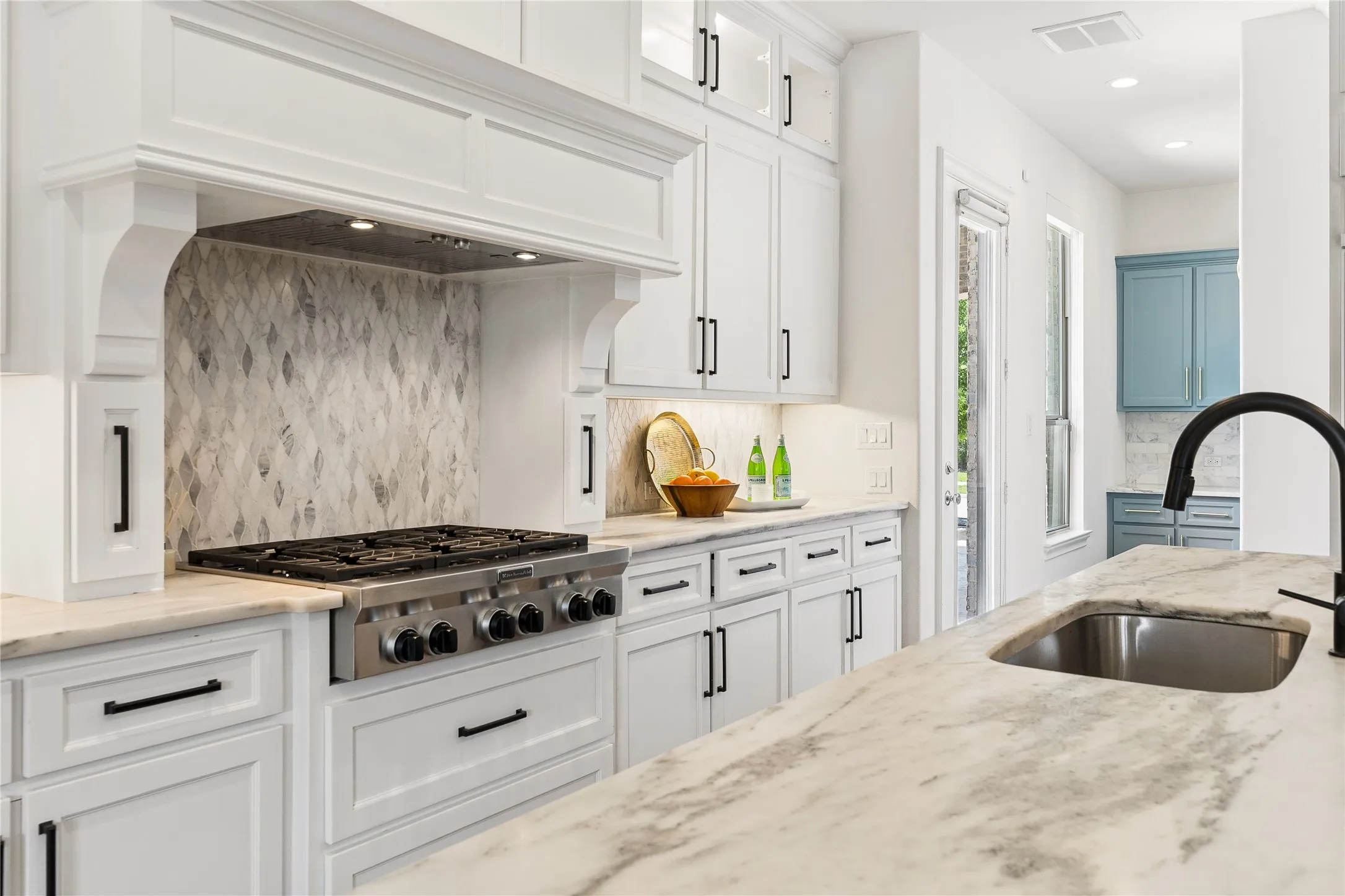 Chef’s kitchen with 6 burner gas cooktop, double oven, oversized island, range hood, and walk-in pantry with planning station.