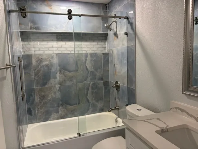 Updated bath with lovely porcelain tile and frameless shower door