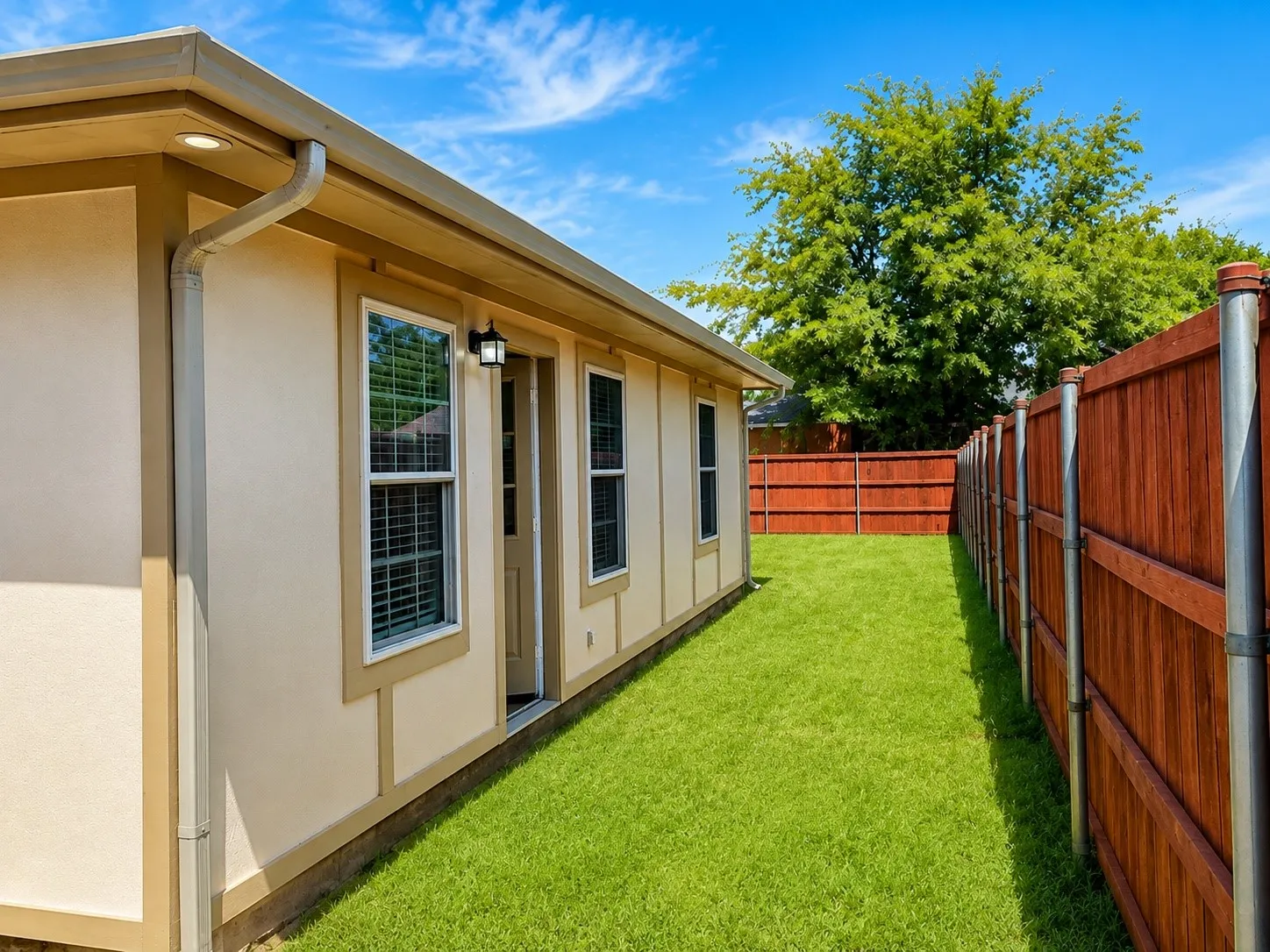 Exterior featuring light-toned siding, privacy fence, and a digitally enhanced green lawn