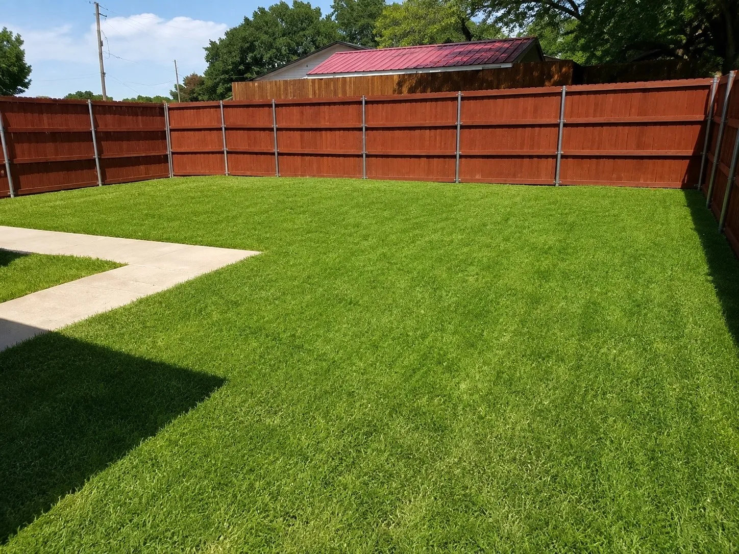 Enclosed yard featuring a digitally enhanced lawn, plus wood fencing, and concrete paving
