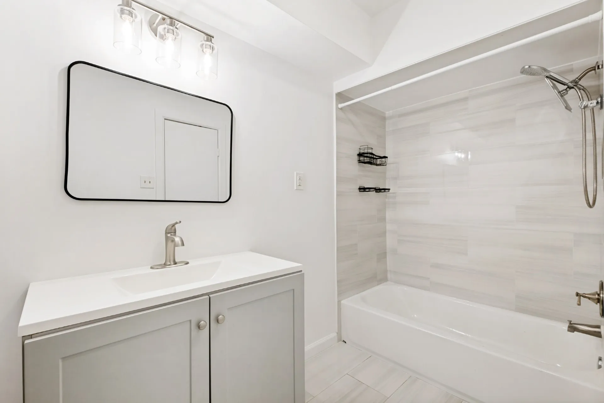 White vanity with a single basin sink, brushed nickel faucet, and a black framed rectangular mirror