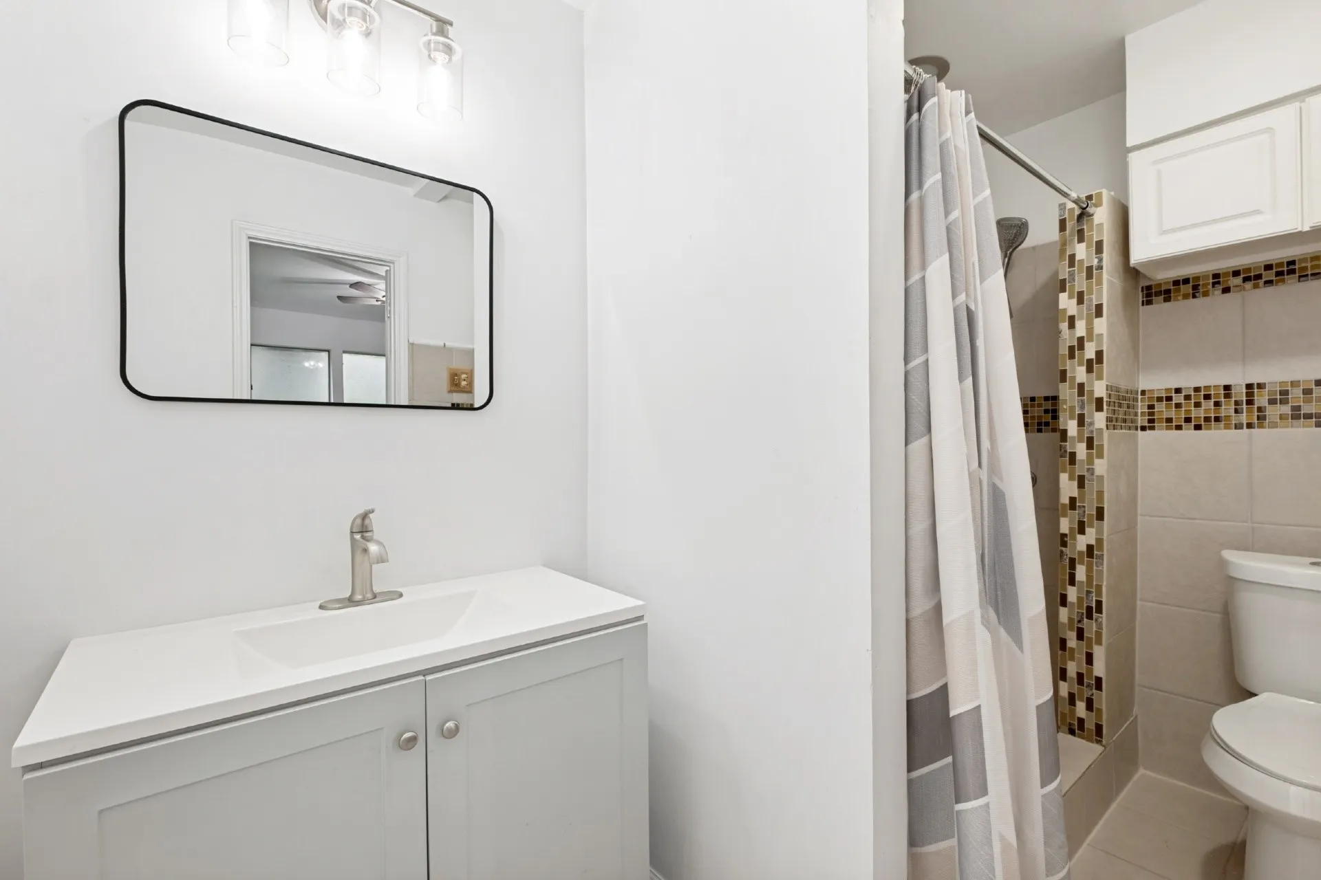 Clean and functional bathroom featuring a white vanity with dual cabinet storage, rectangular sink, and brushed nickel faucet