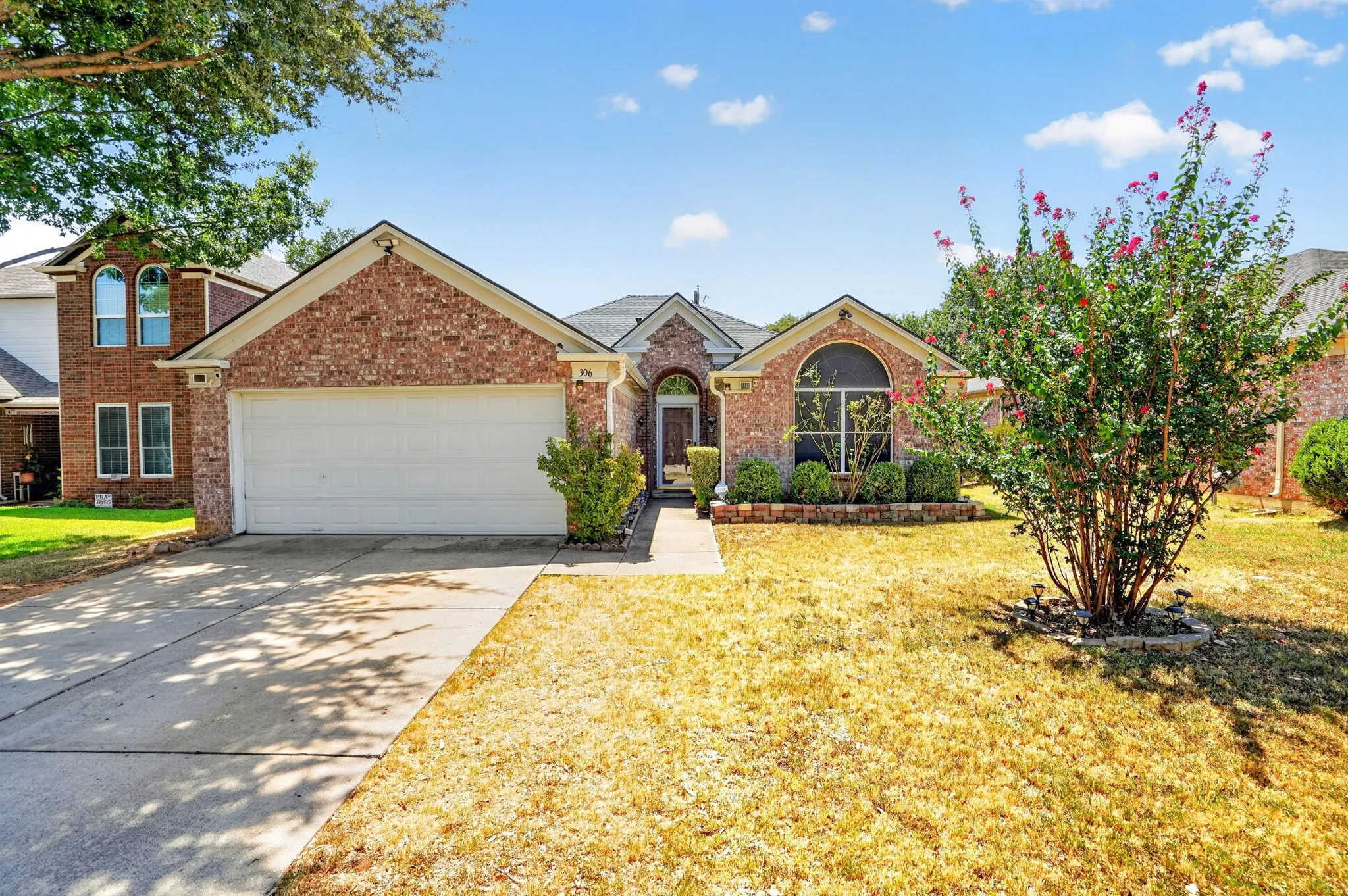 Brick exterior with a gabled roofline, arched window, and attached garage