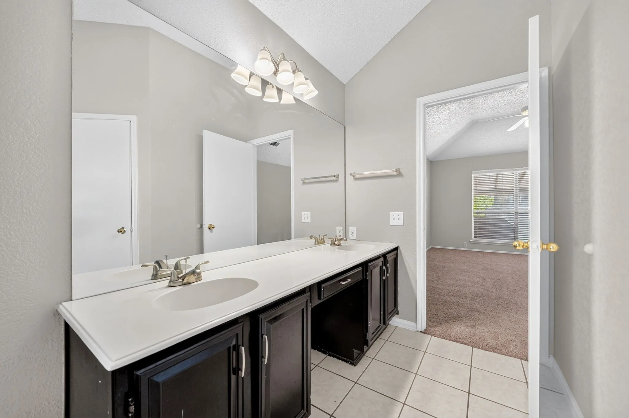 Double vanity with integrated sinks and dark wood-finish cabinetry