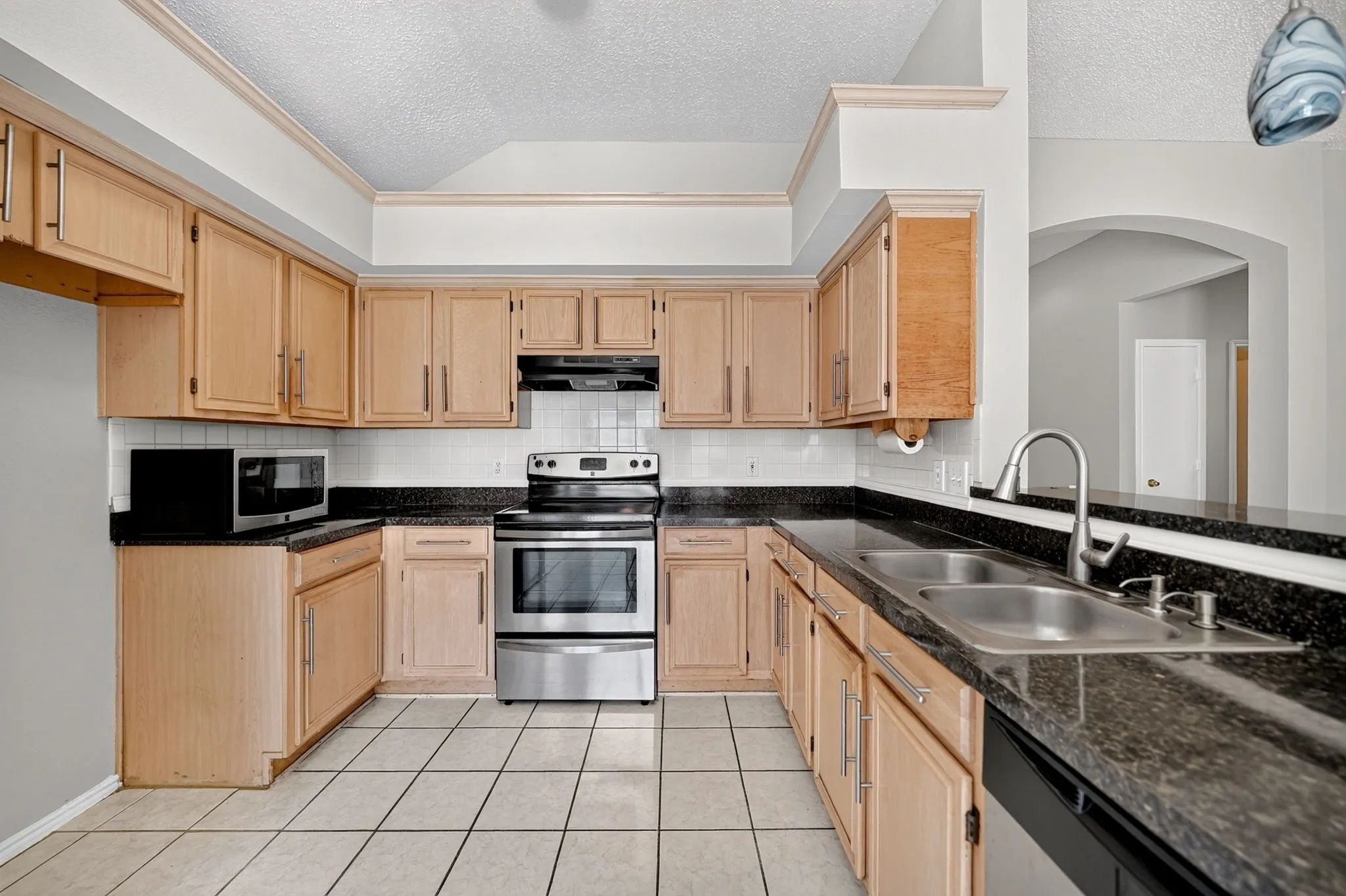 Kitchen featuring wood cabinetry, dark countertops, a tile backsplash, and stainless steel appliances