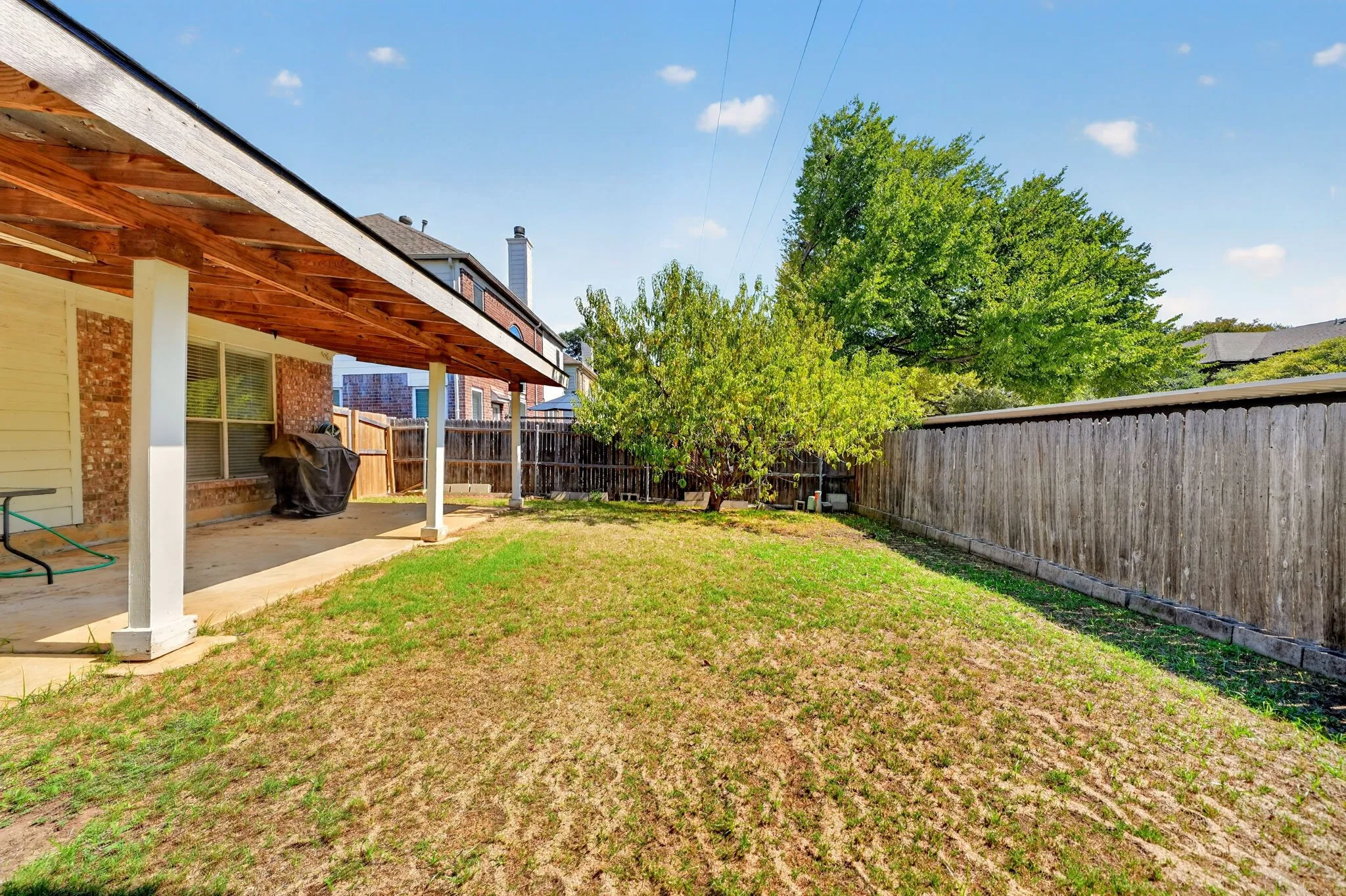 Backyard featuring a covered patio with a wood-finish ceiling, a privacy fence, and mature trees