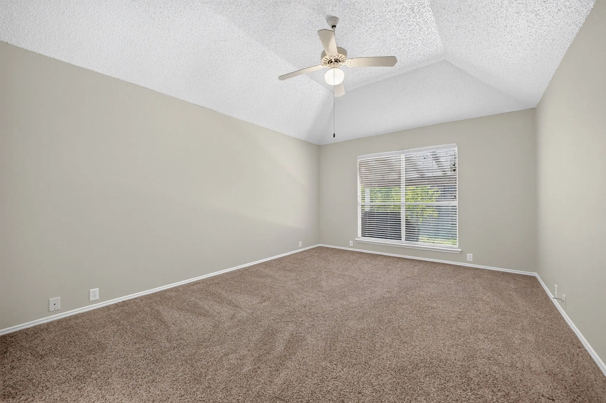 Vaulted ceiling with a ceiling fan, neutral wall tones, and plush carpeting