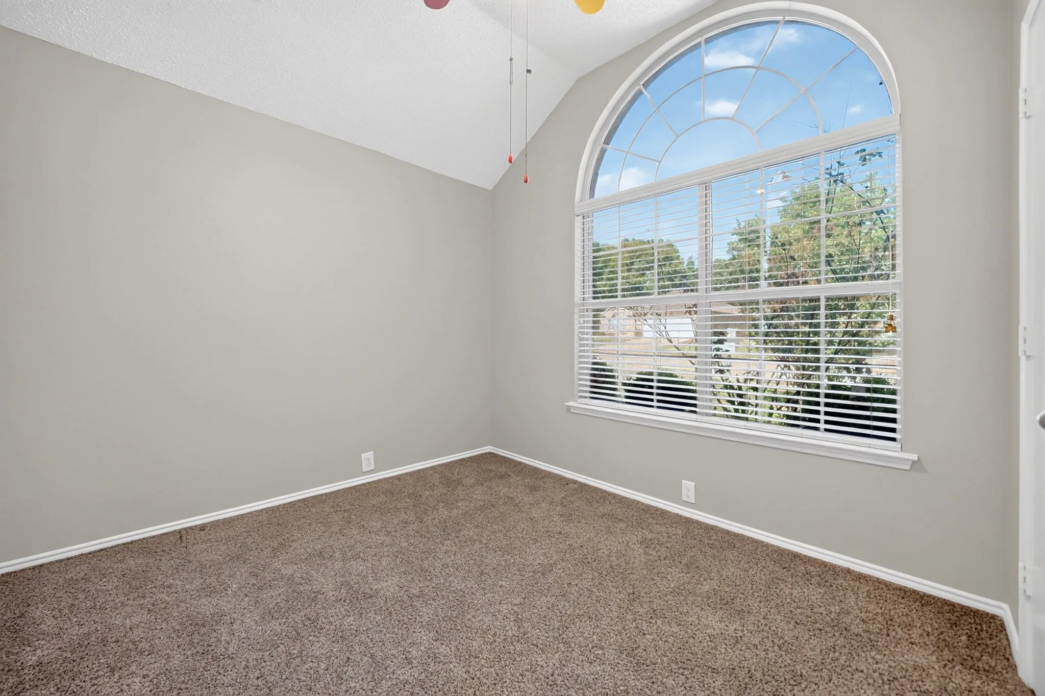 Vaulted ceilings complement an arched window with integrated blinds