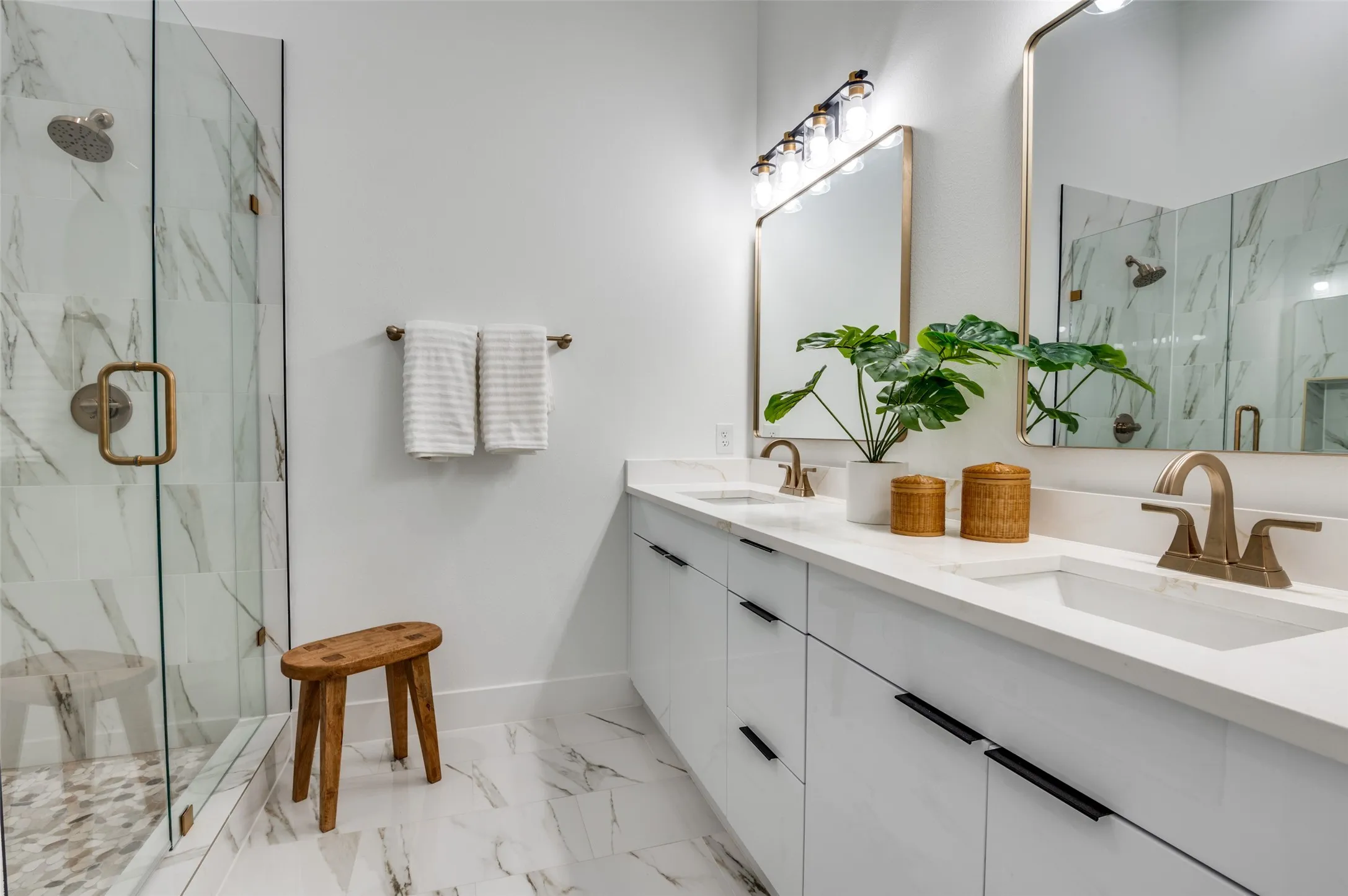 Bathroom with marble look tile flooring, a marble finish shower, and double vanity