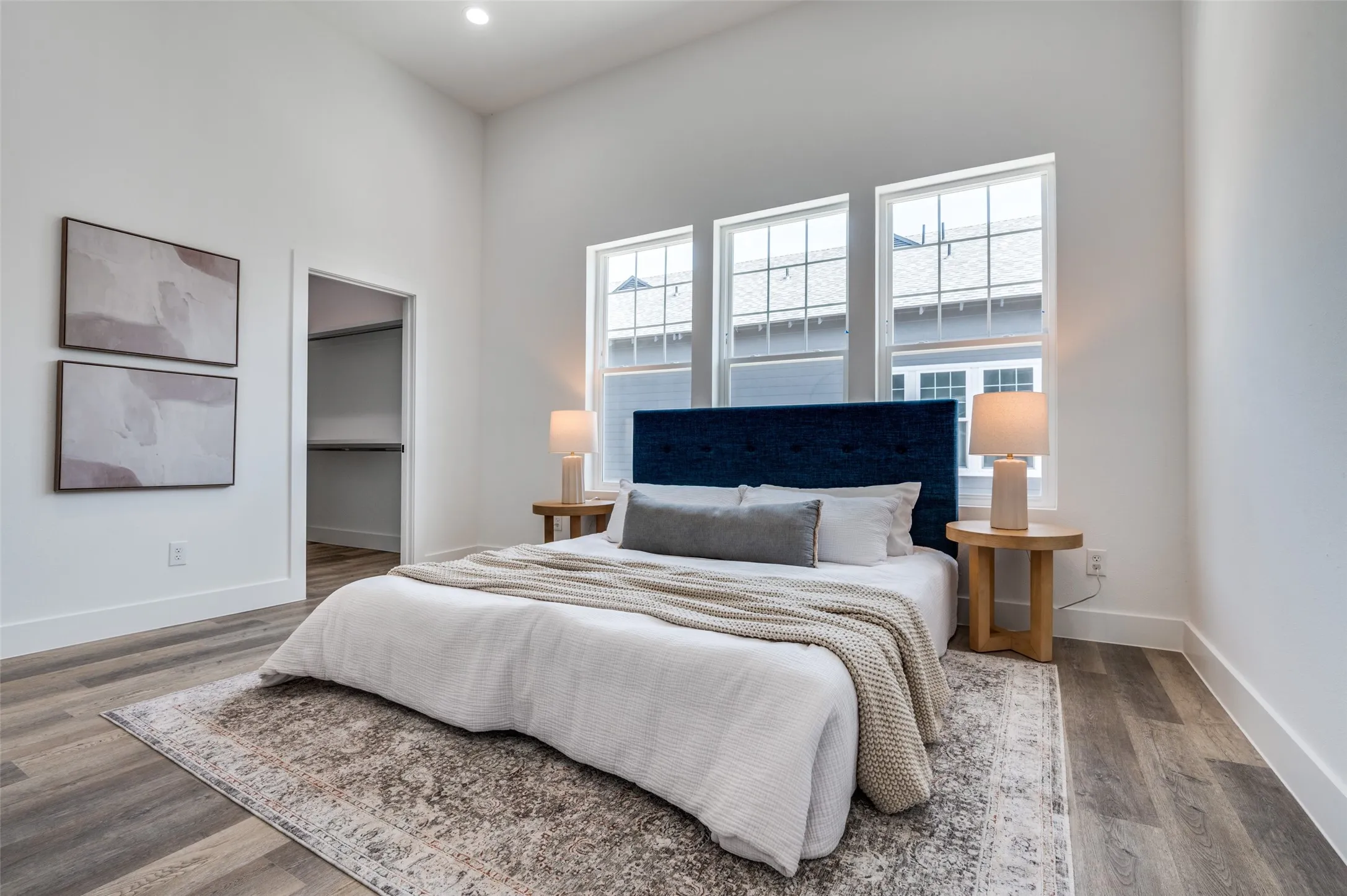 Bedroom with wood finished floors, a walk in closet, and recessed lighting