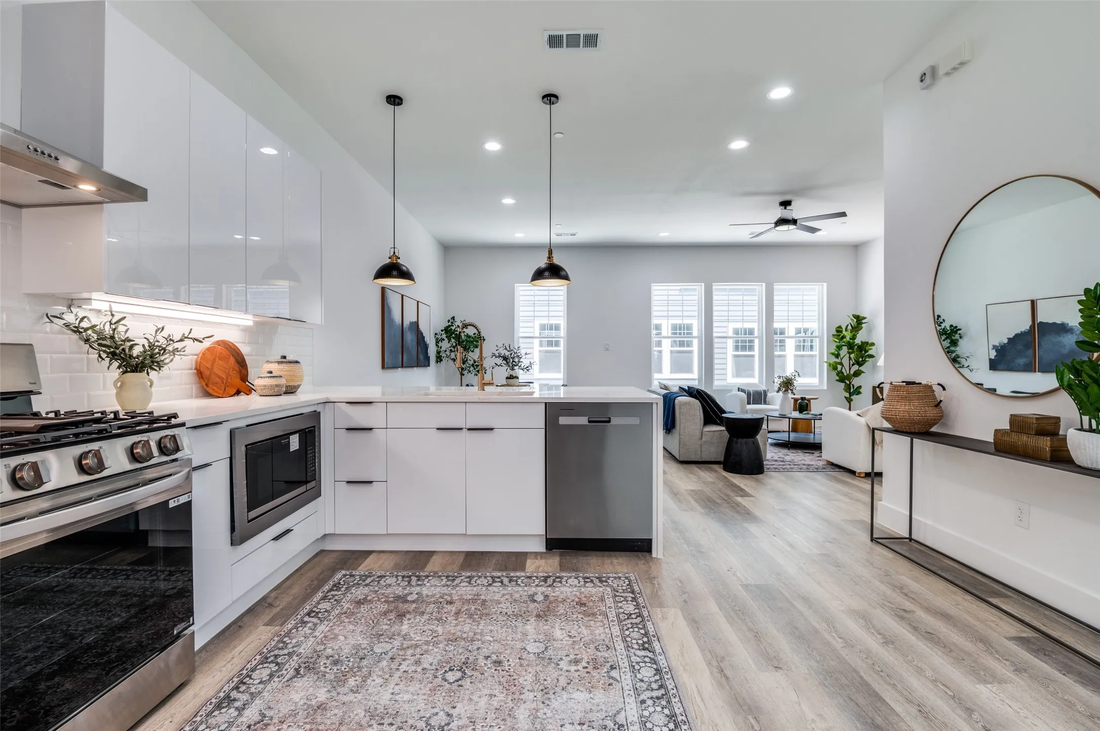 Kitchen featuring appliances with stainless steel finishes, wall chimney range hood, recessed lighting, a peninsula, and white cabinetry