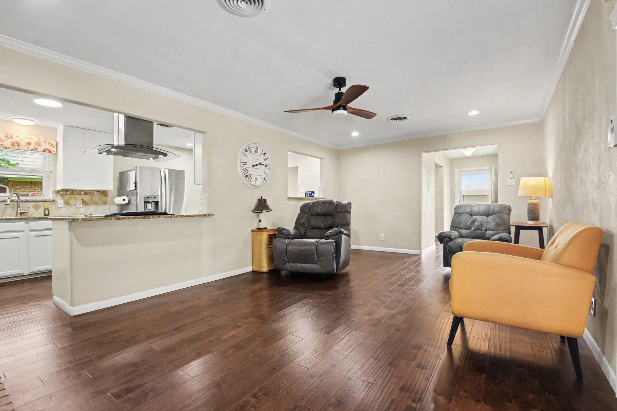 Wood-finish flooring throughout, stainless steel kitchen appliances, granite countertops, white cabinetry, and a ceiling fan