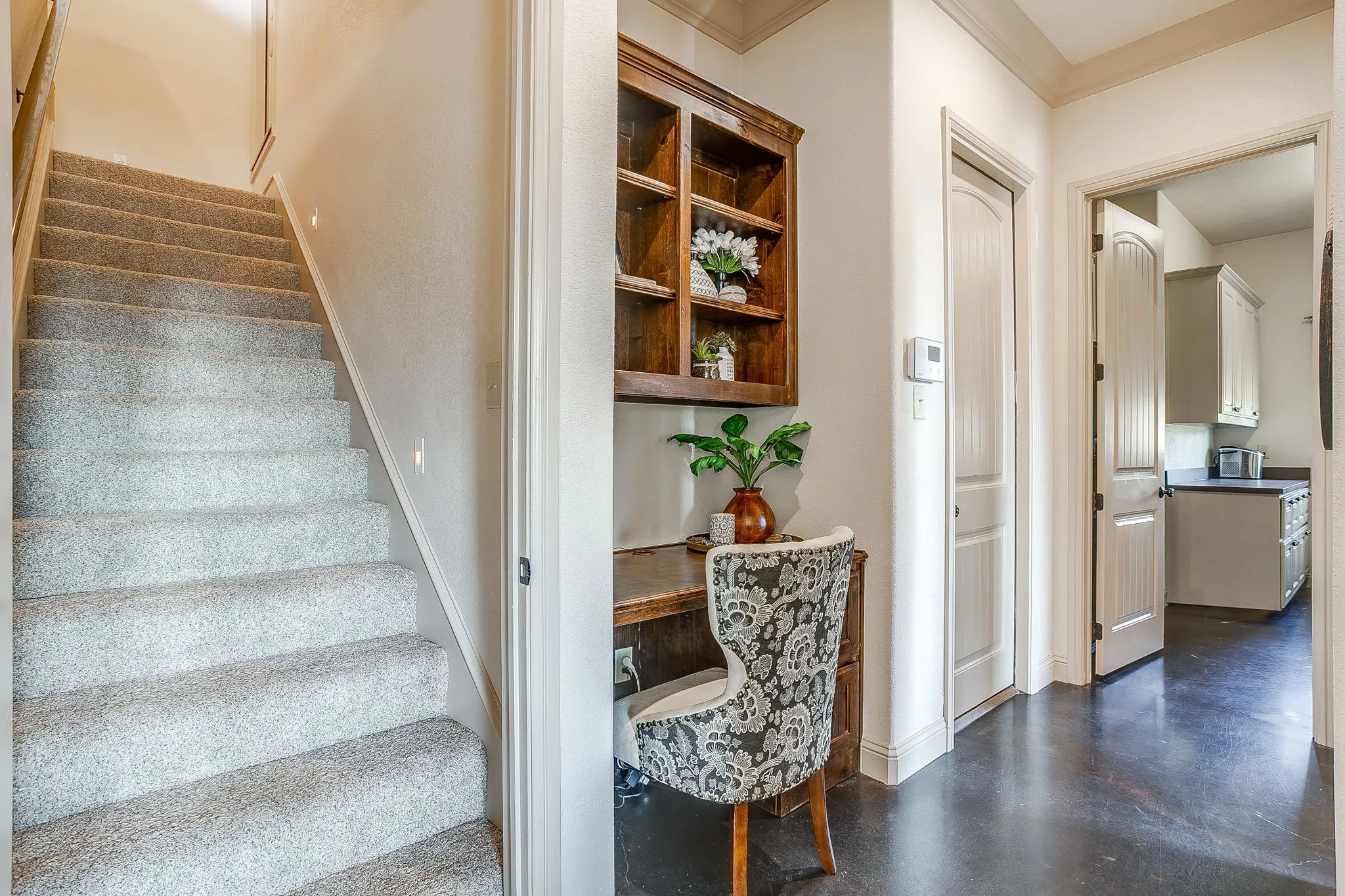 Built-in desk with overhead shelving, carpeted staircase, and wood-finish flooring
