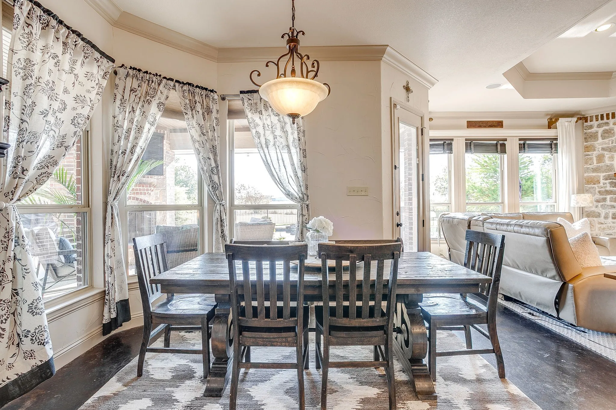 Bay window with crown molding, tray ceiling, wood-finish flooring, and a stone-clad wall feature