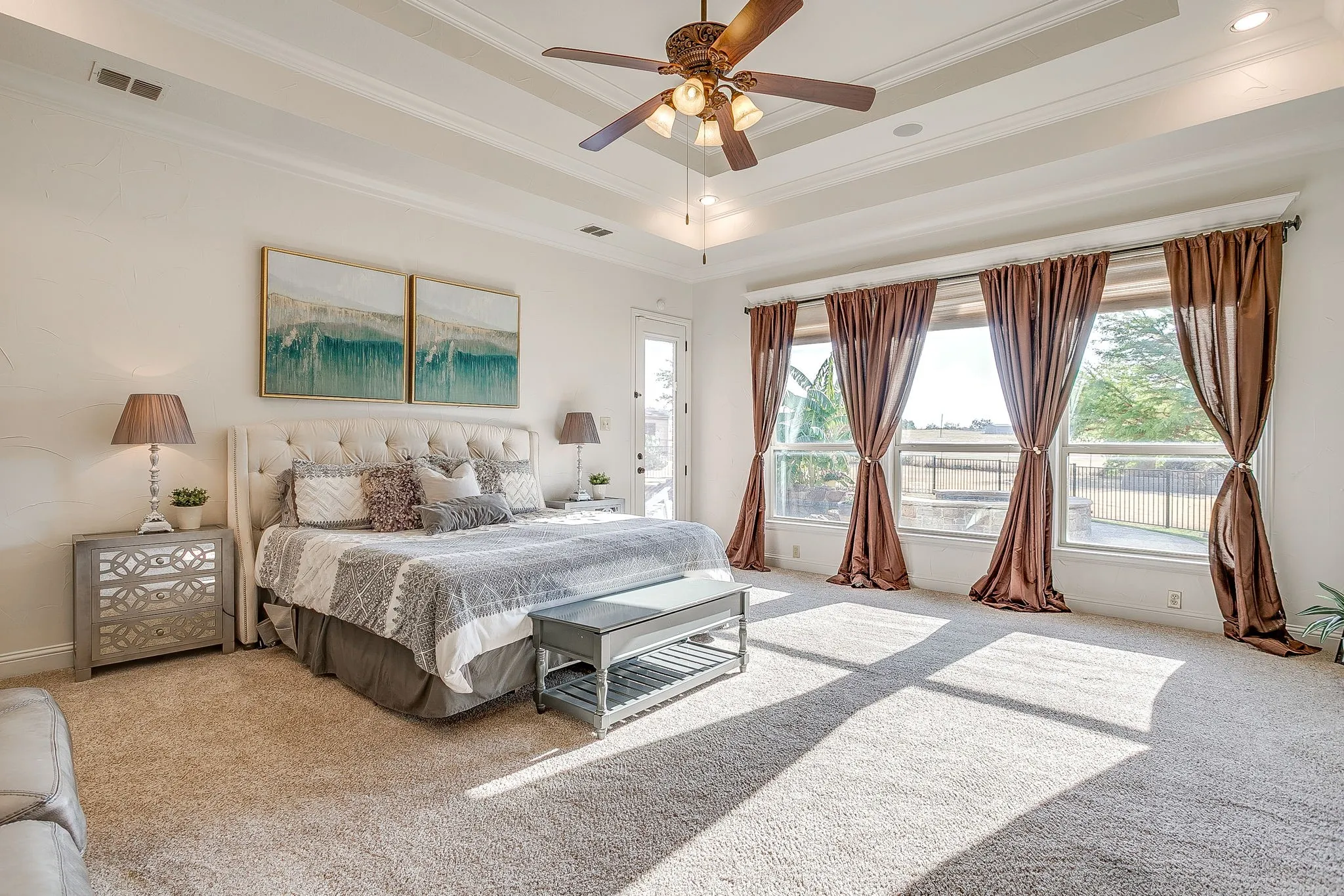 Tray ceiling with a ceiling fan, wall-to-wall carpeting, and multiple windows