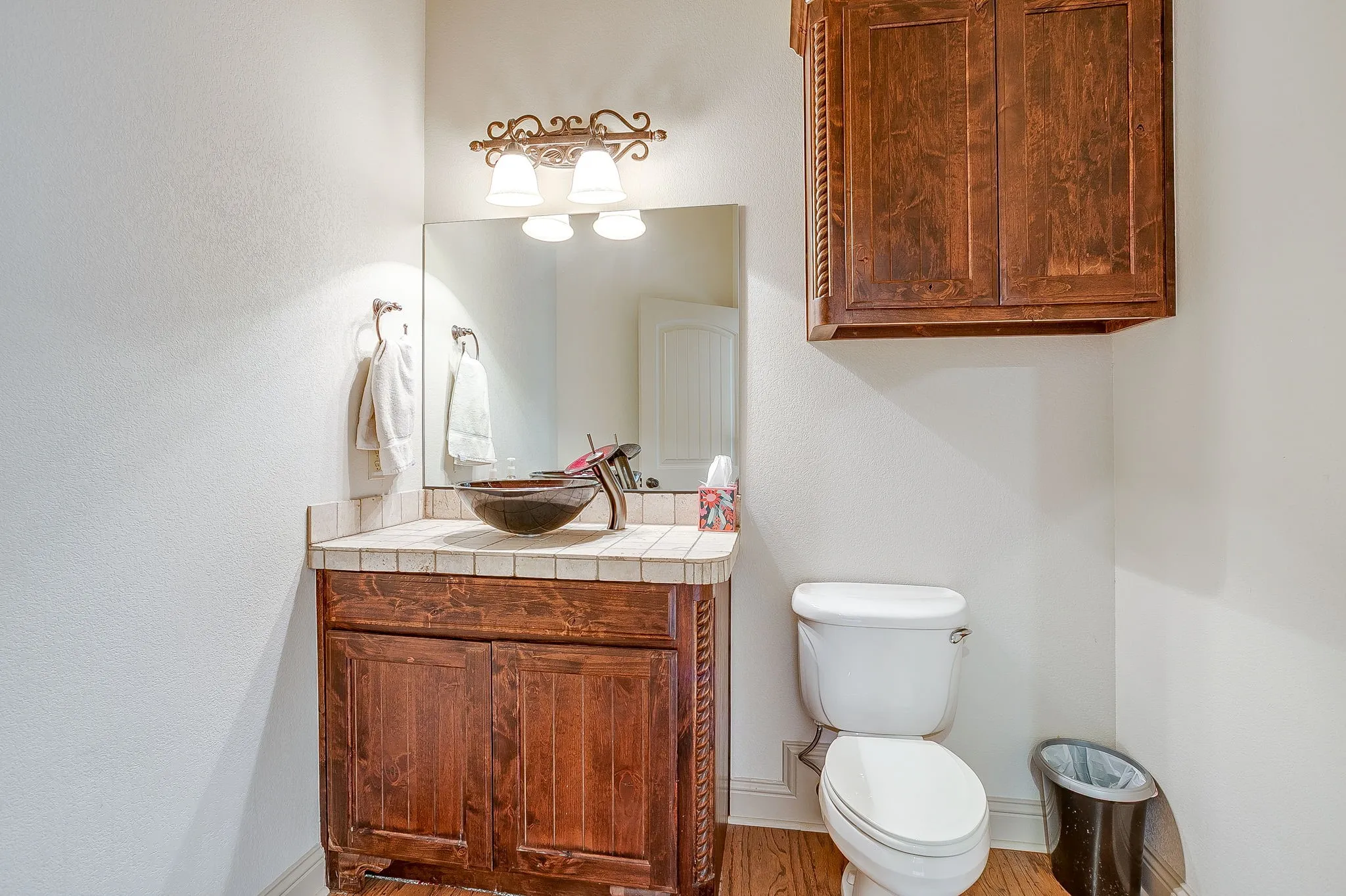 Half-bath upstairs with a Wood-finish vanity with a tile countertop, vessel sink, and wall-mounted mirror