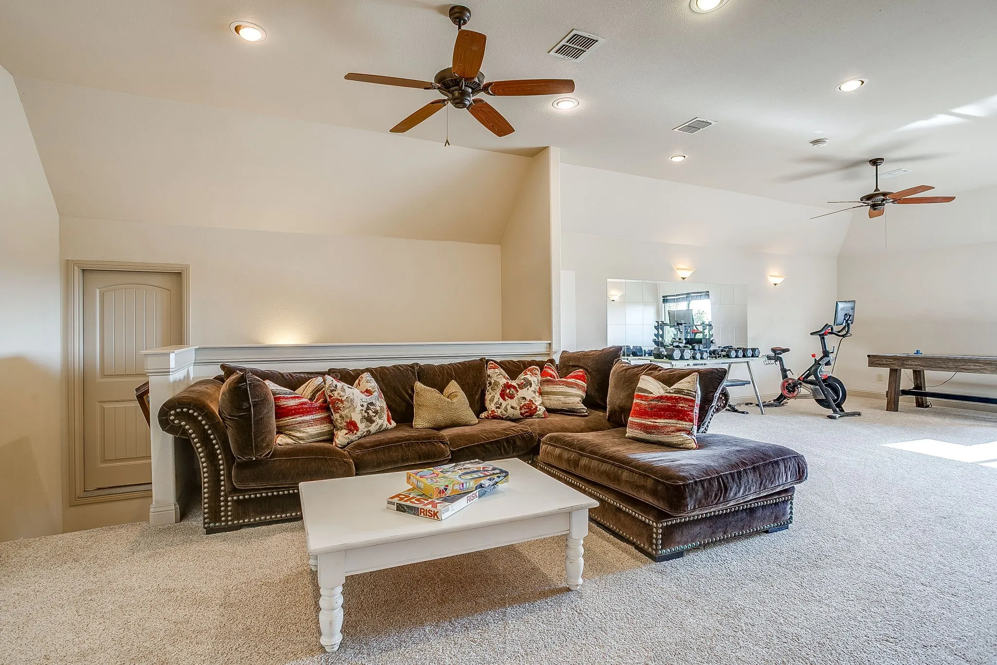 Expansive carpeted room with vaulted ceilings, recessed lighting, and multiple ceiling fans