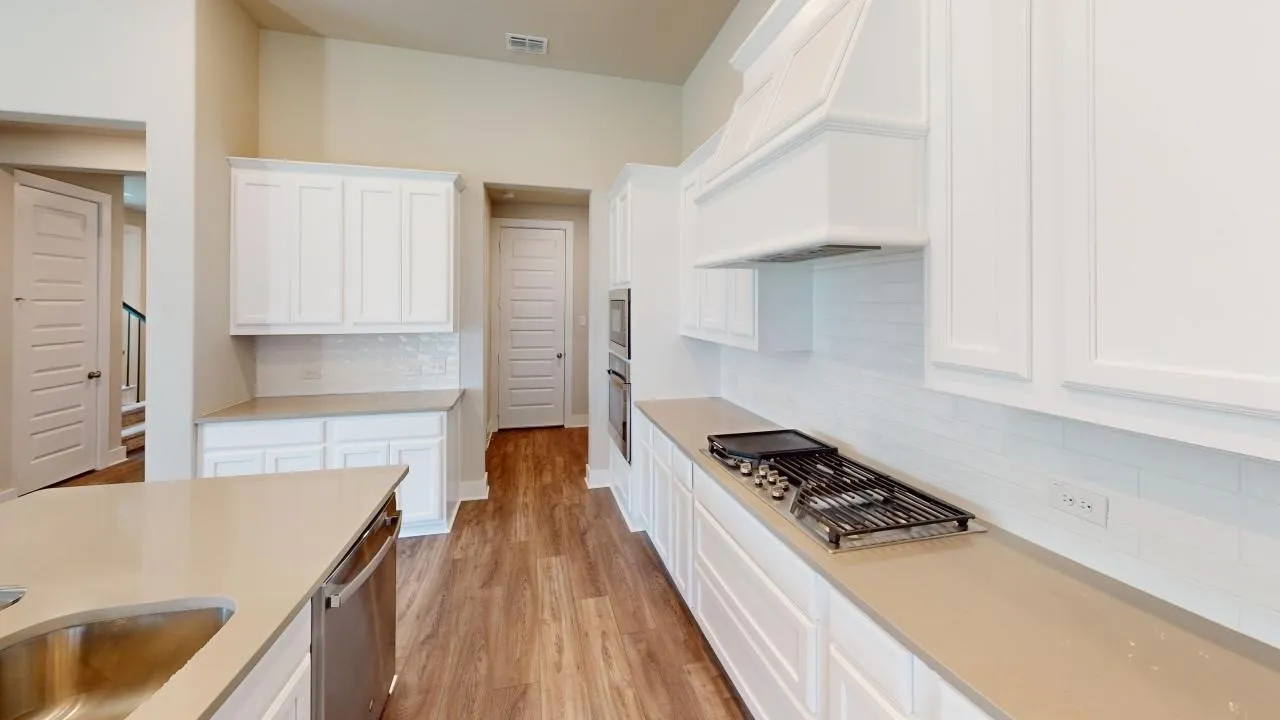 Gourmet kitchen featuring a built-in oven, gas cooktop, built-in microwave, white shaker cabinetry, and wood-finish flooring