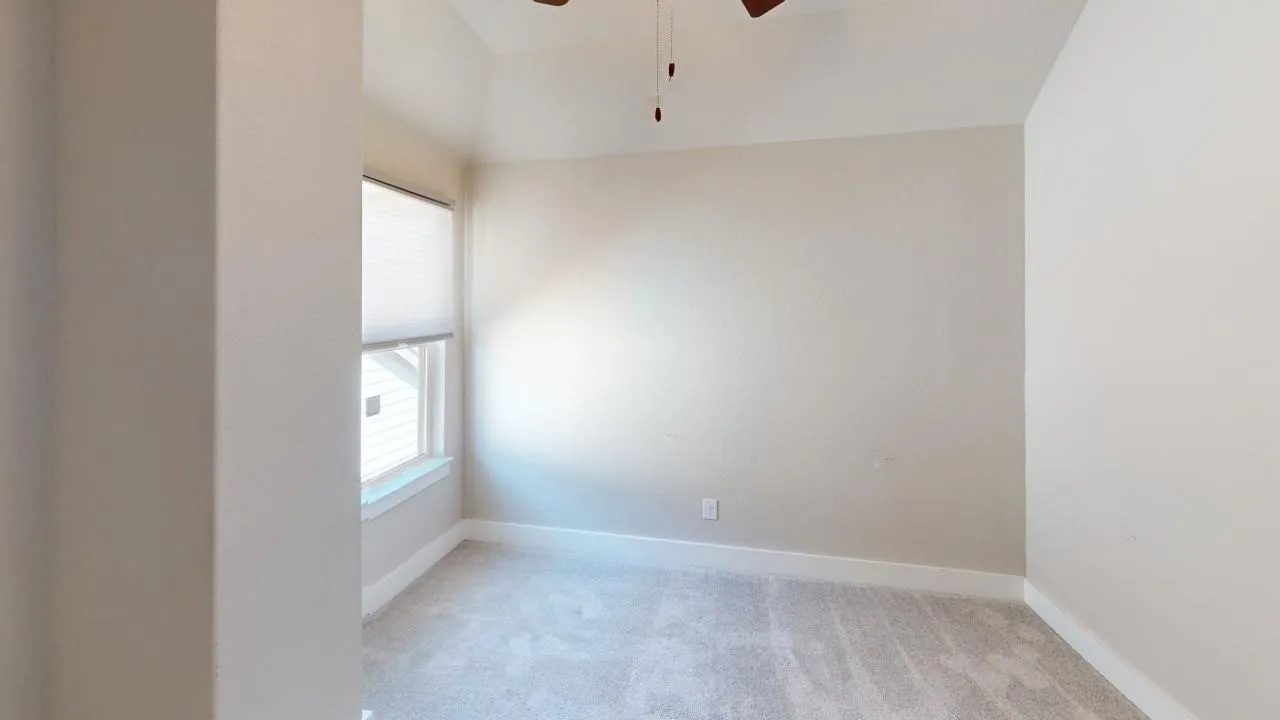 Recessed window with a white frame, neutral-toned wall paint, gray carpet, and a ceiling fan with dark blades
