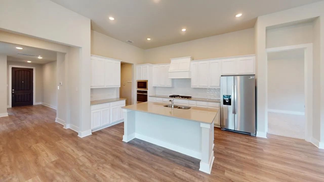 Open-concept living area featuring wood-finish flooring, recessed lighting, and a kitchen island with an integrated sink