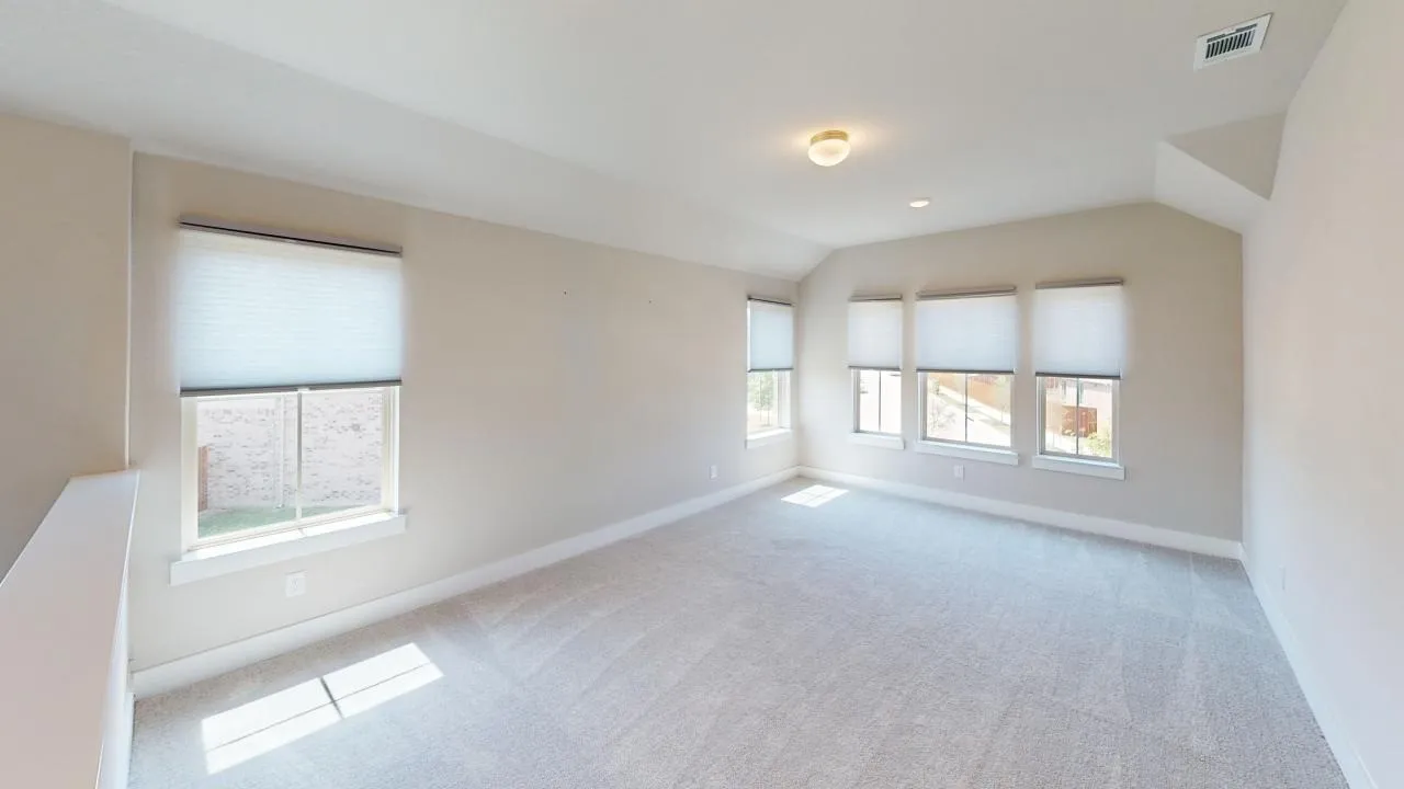 Neutral-toned carpeting with multiple windows and light-filtering shades