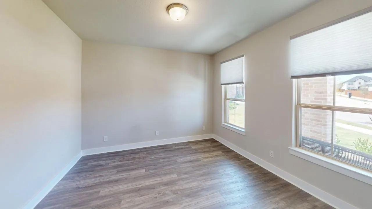 Wood-finish flooring, neutral wall tones, multiple windows, and a flush-mount ceiling fixture