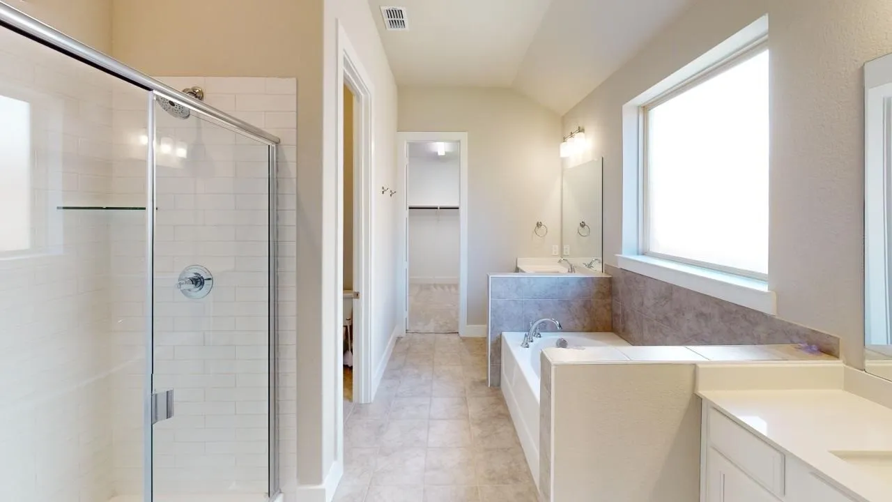 Walk-in shower with clear glass enclosure and subway tile surround